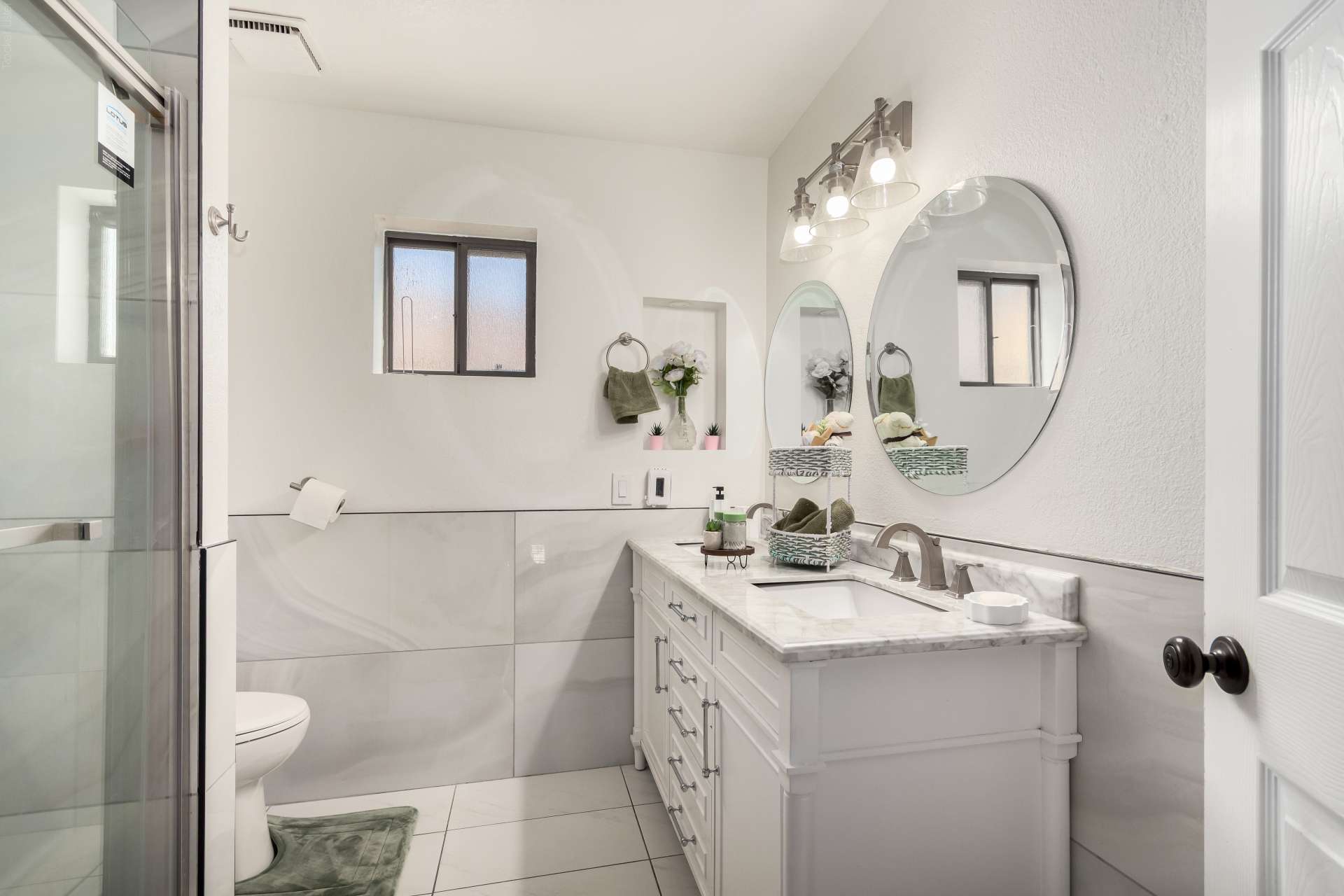 26 of 34. Stylish guest bathroom featuring a contemporary vanity, updated lighting, elegant mirrors, and a beautifully renovated walk-in shower with premium finishes.