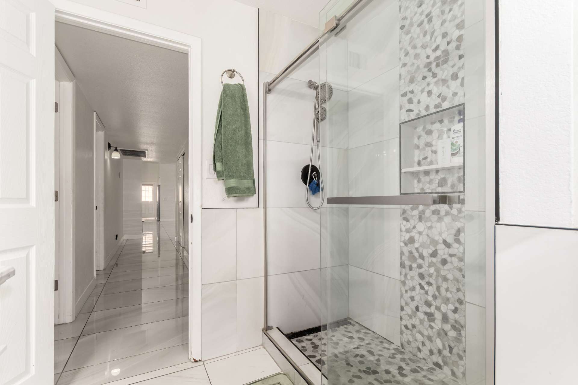 28 of 34. Alternate angle highlighting the spacious frameless shower, upgraded tile work, recessed shelving, and sleek finishes that complete this beautifully remodeled bathroom.