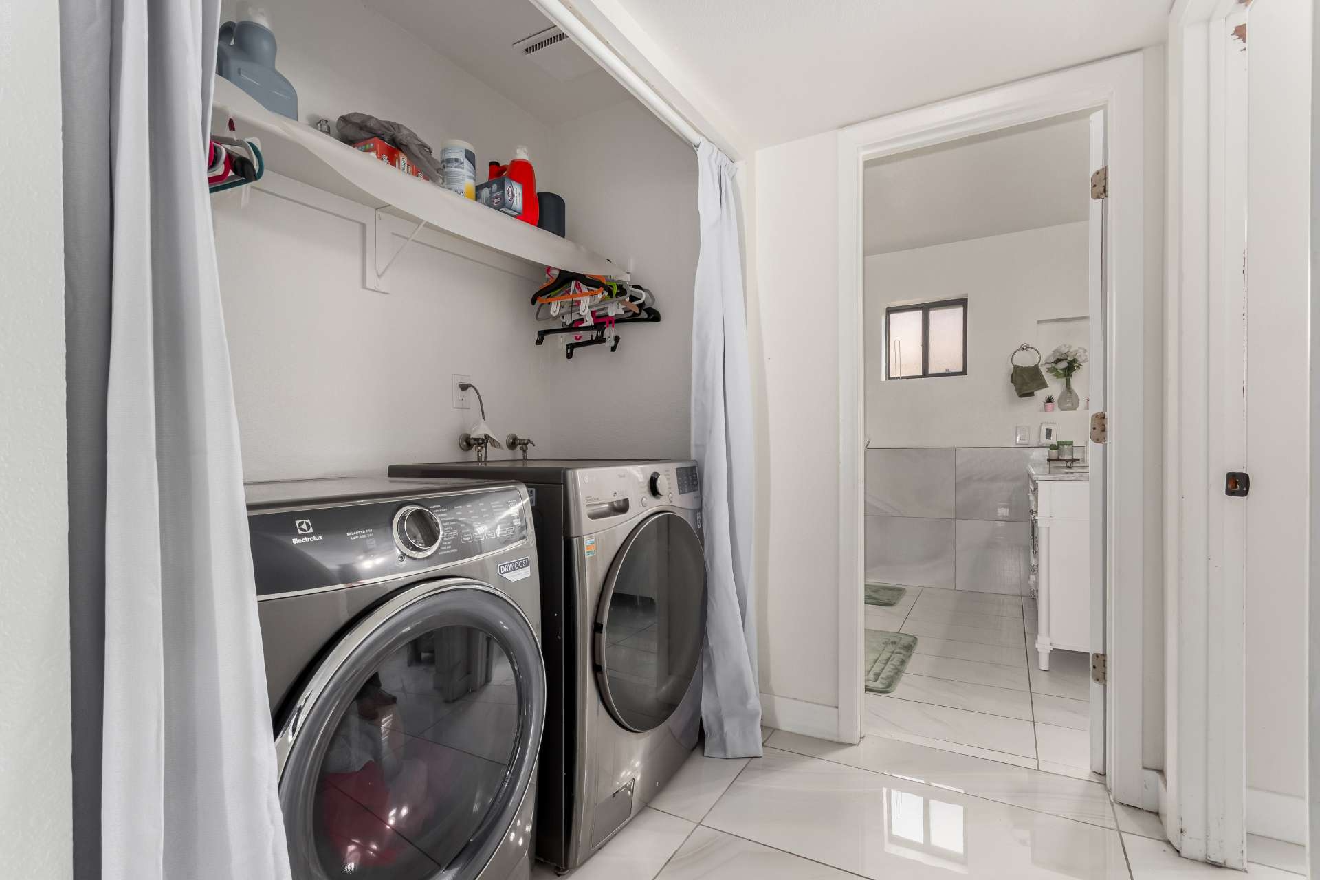 29 of 34. Dedicated laundry space with front-load appliances, utility sink, open shelving, and convenient storage designed to simplify daily household tasks.