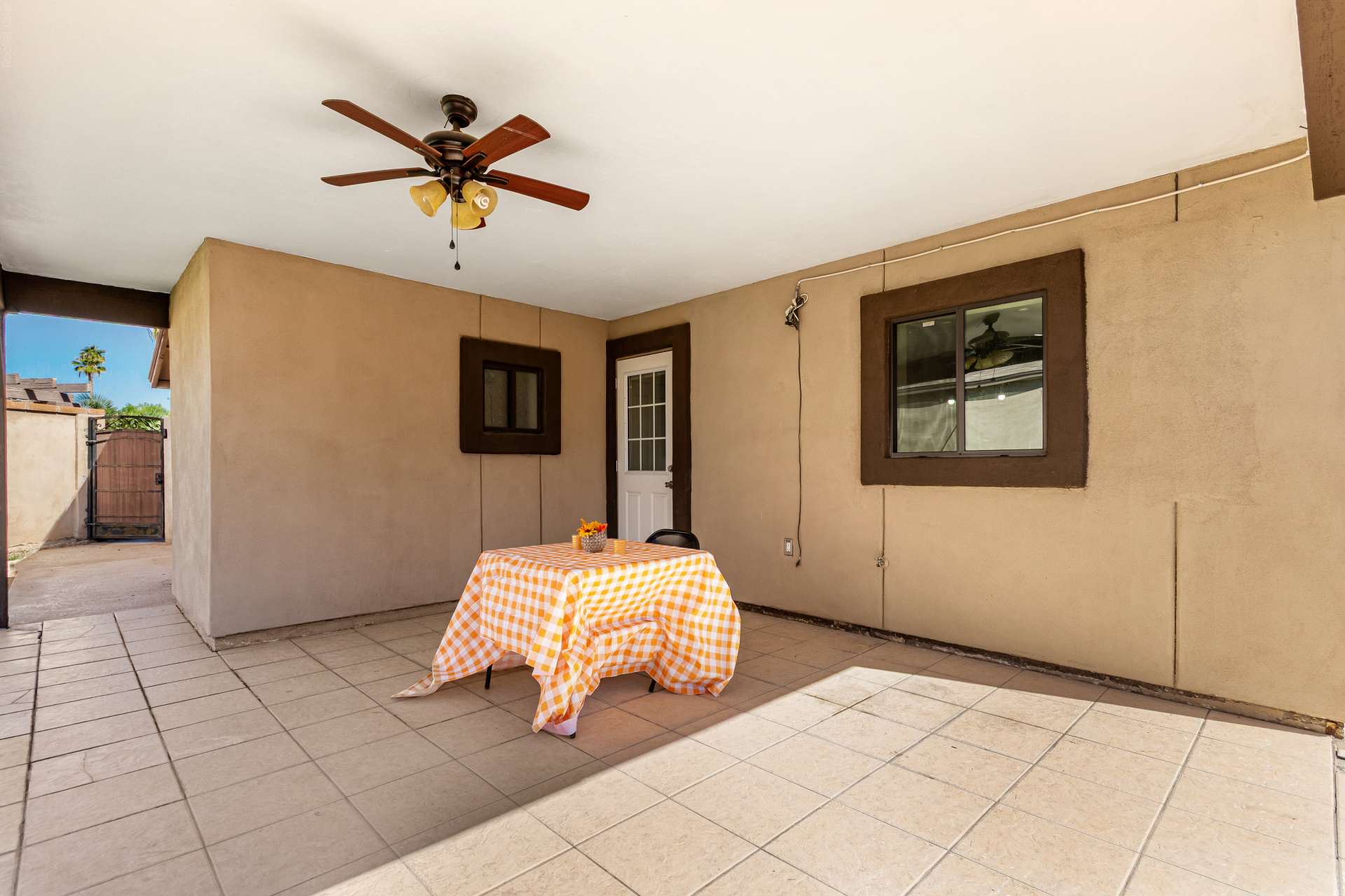 31 of 34. Covered patio with ceiling fan, durable tile flooring, and space for outdoor seating creates a comfortable extension of the home's living area. Ideal for entertaining or relaxing year-round in Scottsdale.
