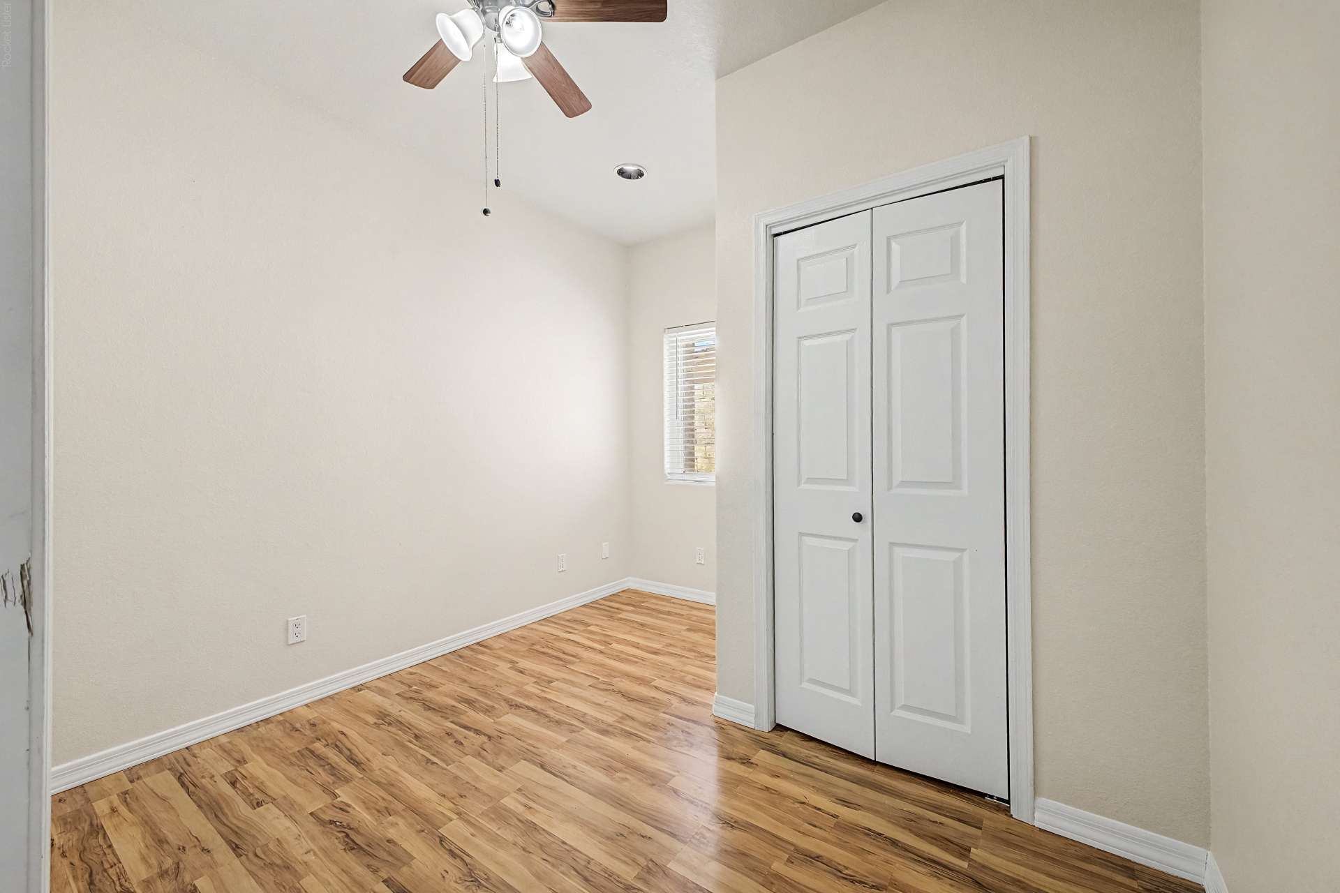 14 of 47. A bright secondary bedroom with updated flooring, vaulted ceilings, ceiling fan, and closet space provides comfort and versatility for guests, family, or a dedicated workspace.