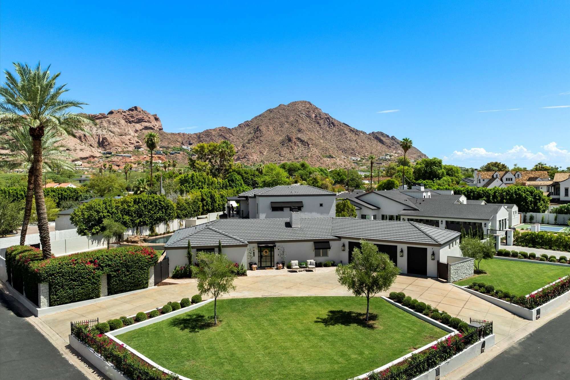 1 of 48. Elevated aerial view highlighting manicured landscaping, circular drive, and Camelback Mountain backdrop at this luxury Arcadia Proper home in Phoenix.