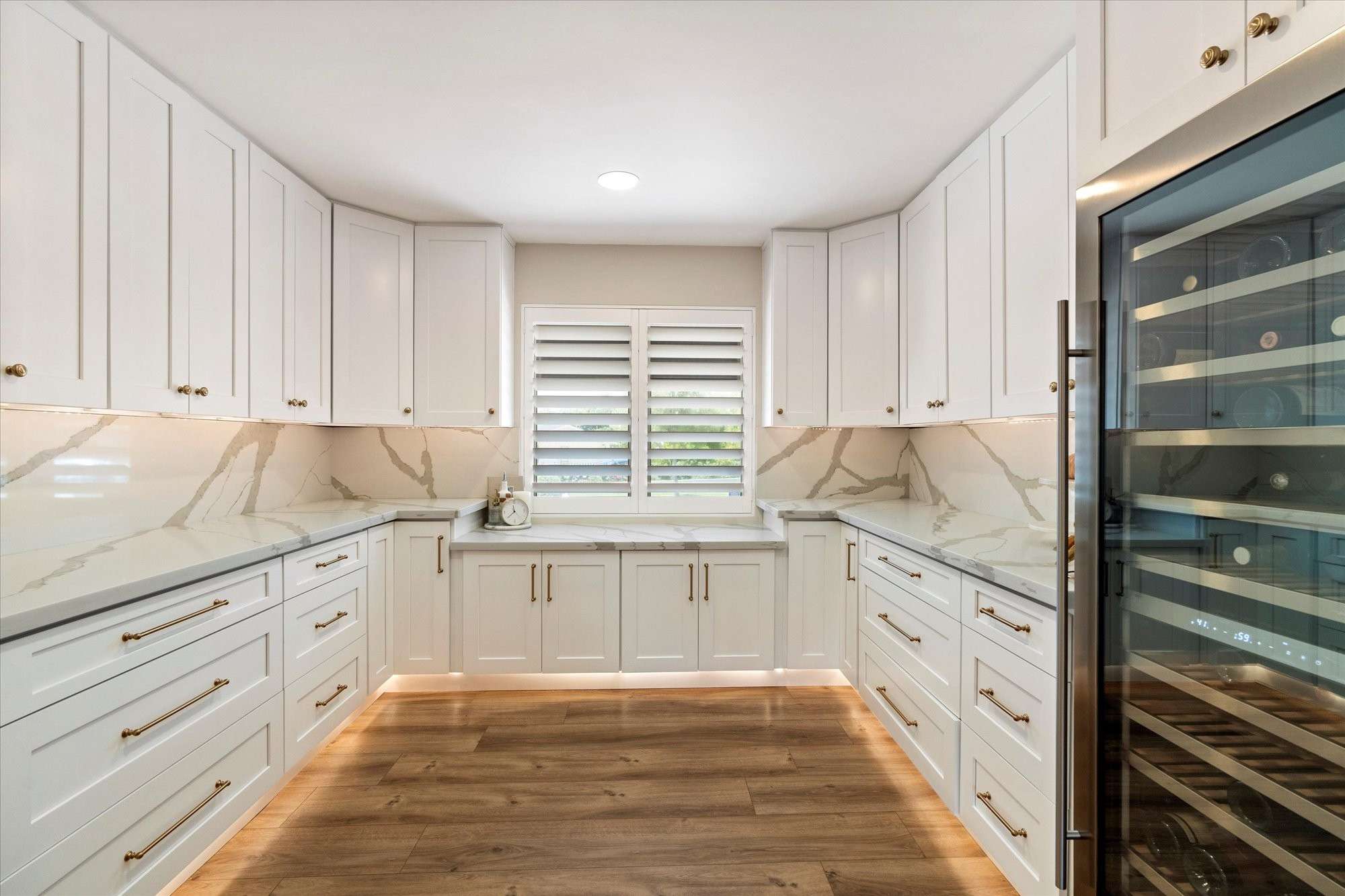 7 of 48. Impressive Butler s pantry with extensive storage, stone countertops, and integrated wine refrigeration for effortless organization.