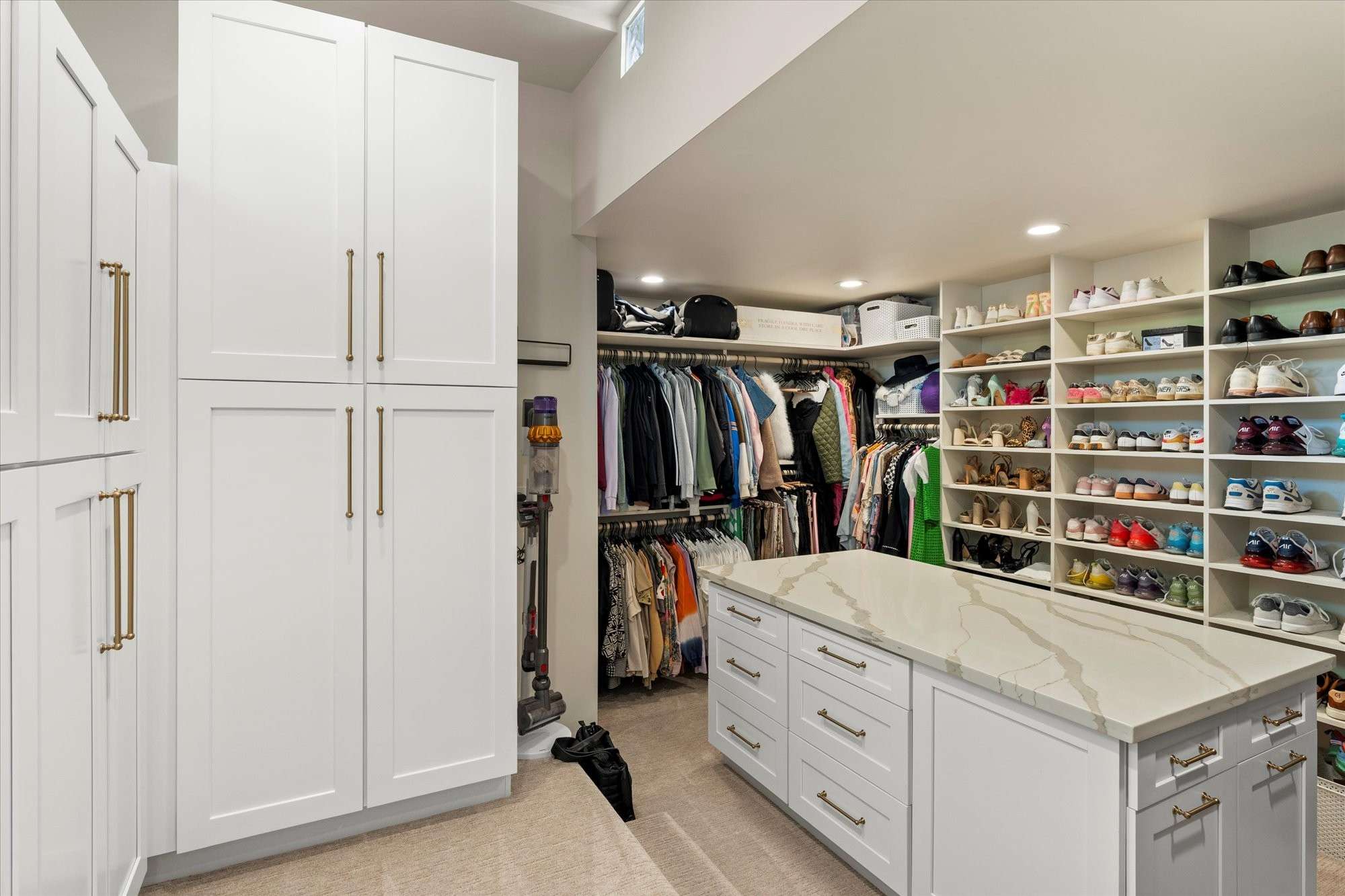 22 of 48. Custom walk-in closet with built-in shelving, center island, and ample space for clothing, shoes, and accessories.