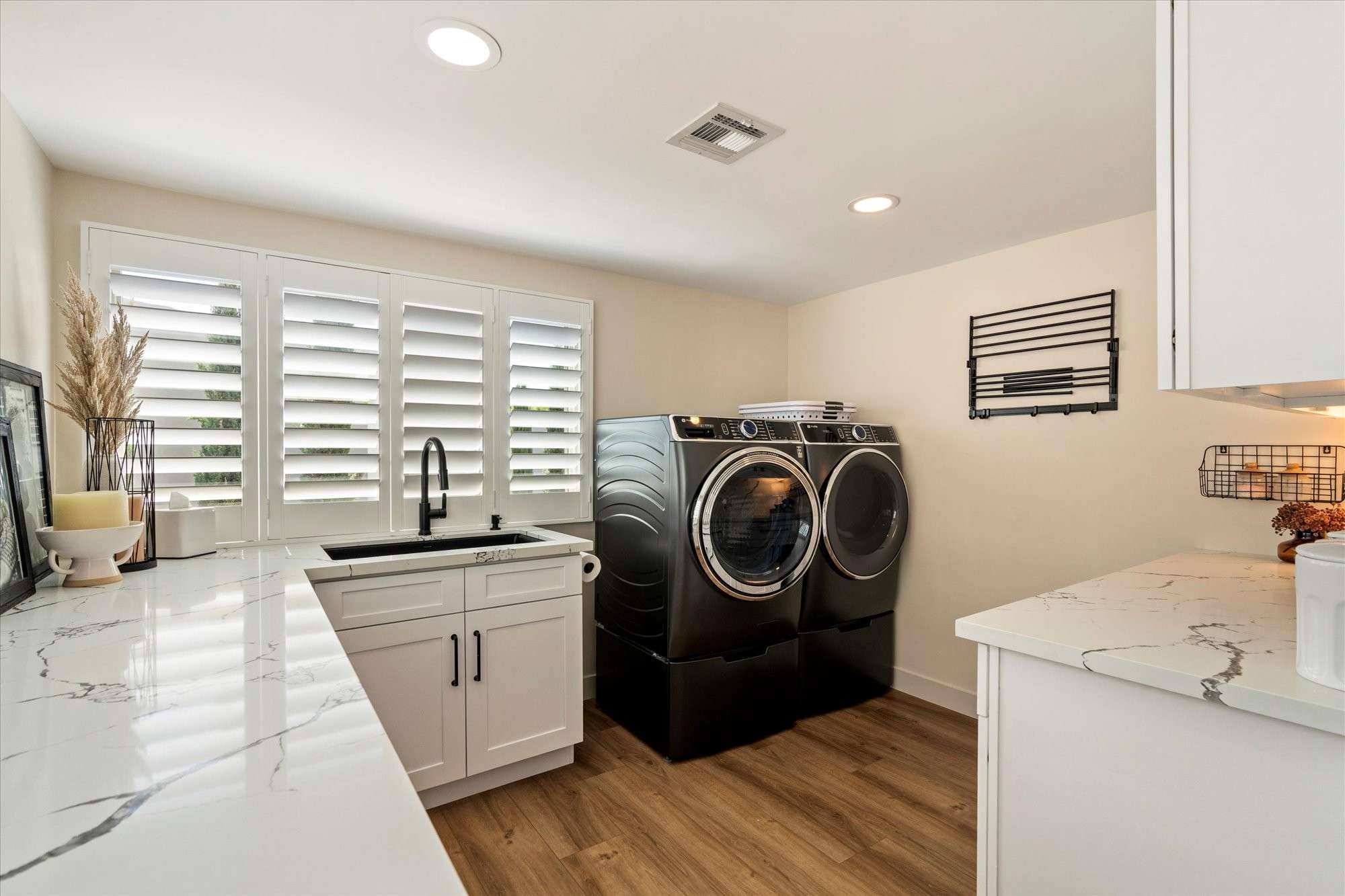 31 of 48. Functional laundry room with quartz countertops, utility sink, storage cabinetry, and efficient workspace design.