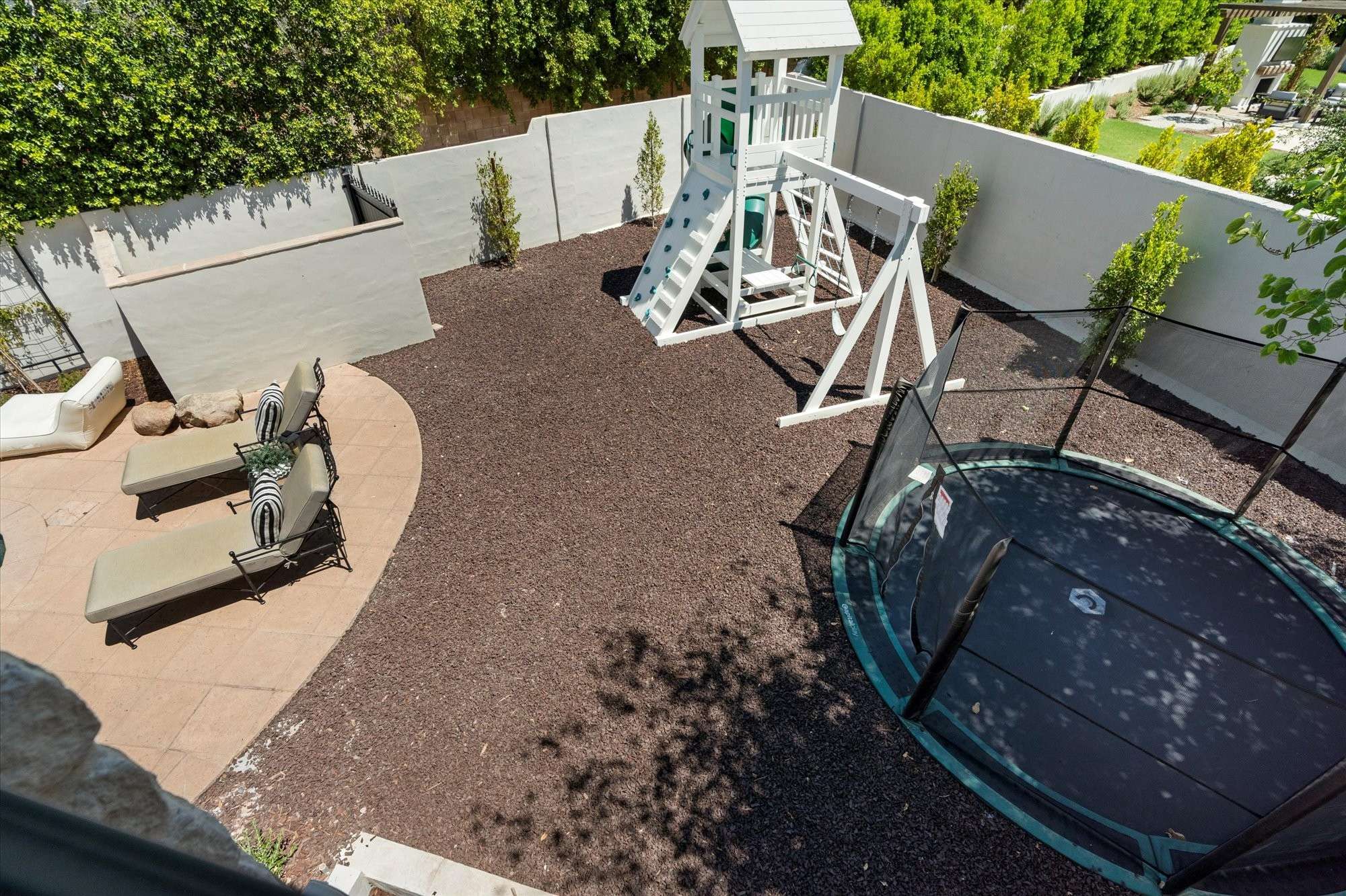 17 of 48. Backyard play zone featuring an in-ground trampoline and play structure, offering a fun and functional outdoor setup.