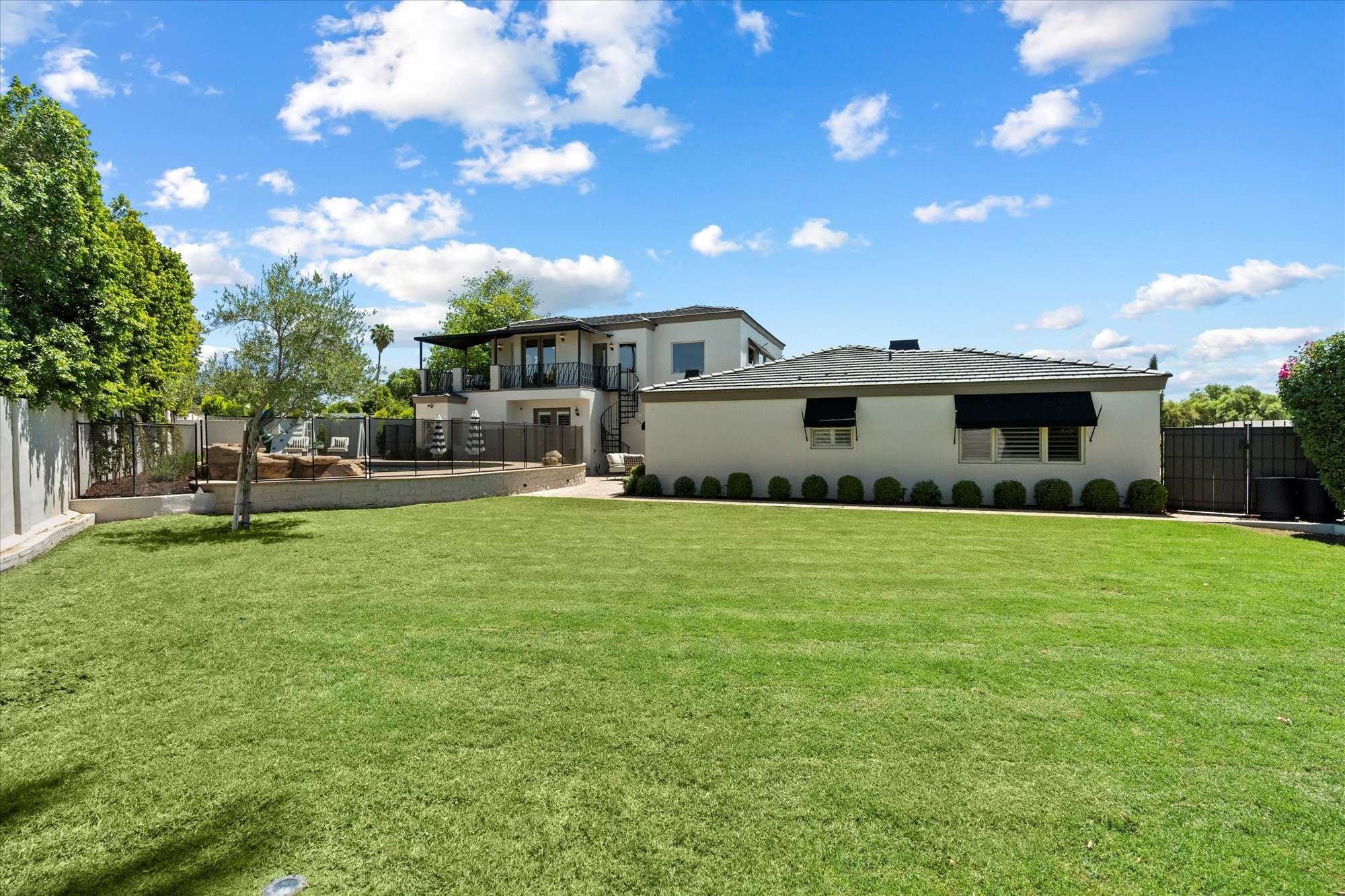 45 of 48. Wide-open grassy backyard ideal for gatherings, play, or relaxation, surrounded by mature trees and manicured landscaping.