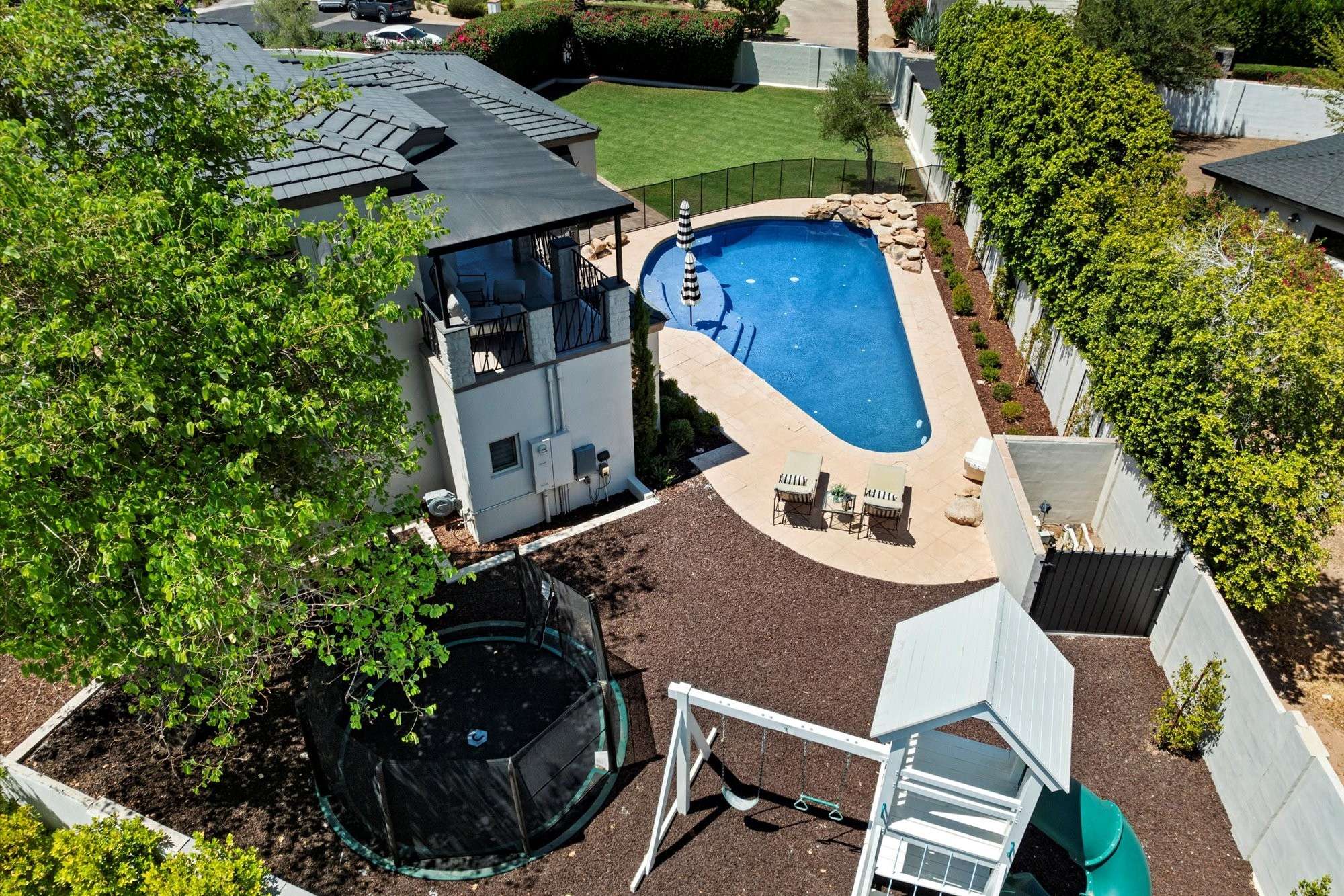 6 of 48. Aerial perspective showcasing the play structure, trampoline, and pool, highlighting the property s outdoor versatility.