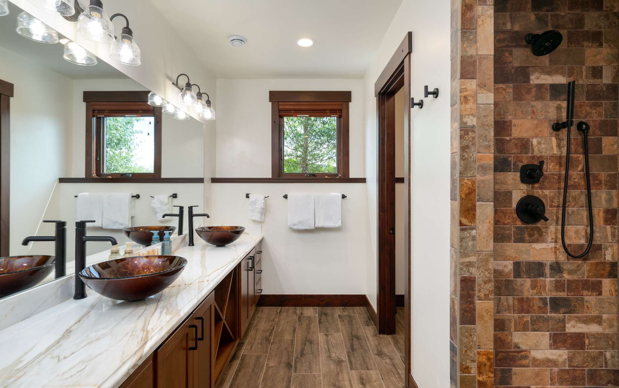 24 of 42. Spacious bathroom featuring dual sinks, a unique stone shower, and ample natural light.