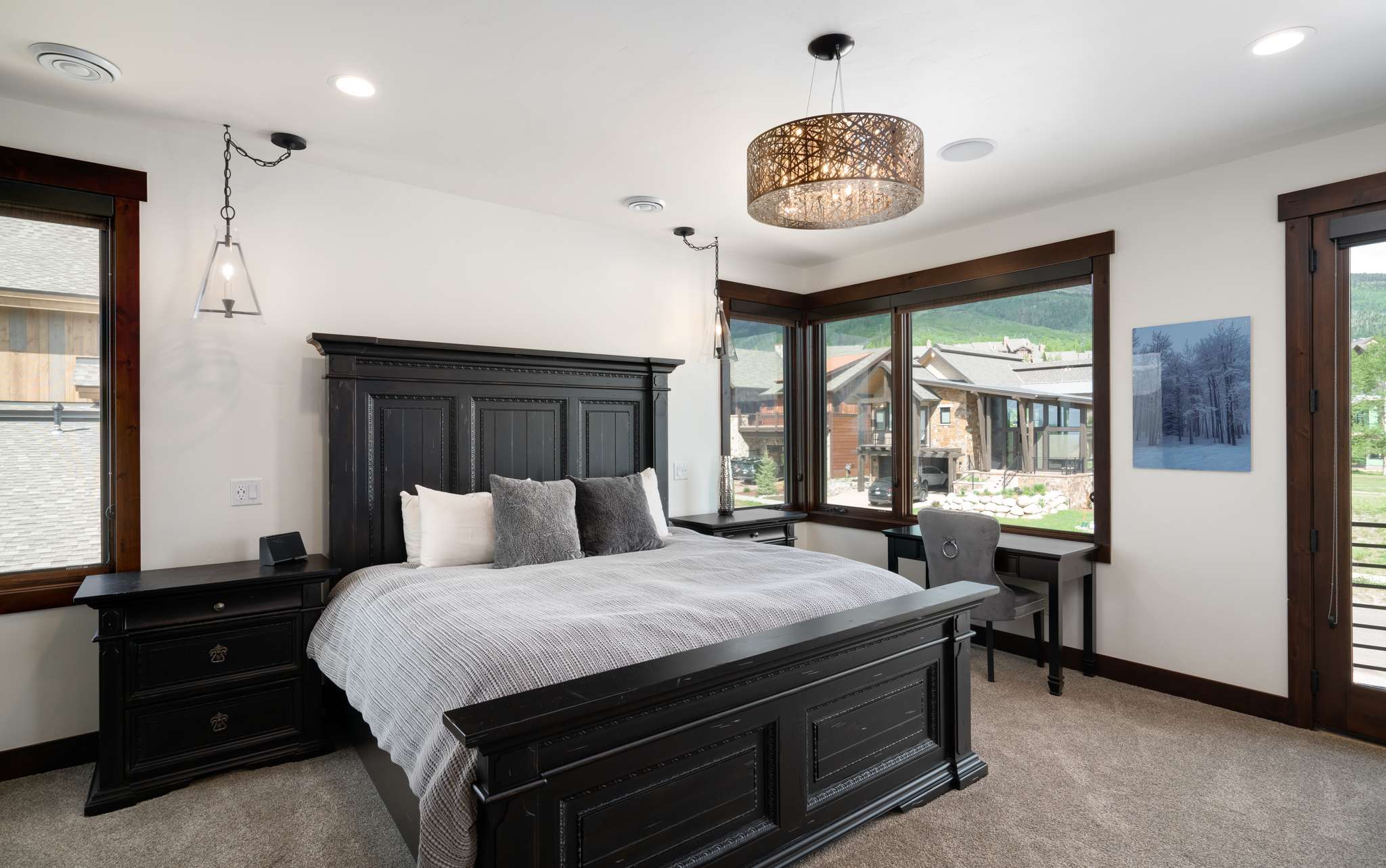 16 of 42. Luxurious primary bedroom featuring a stunning stone fireplace and modern lighting, a five-piece en suite bath, mountain views, and a private balcony.