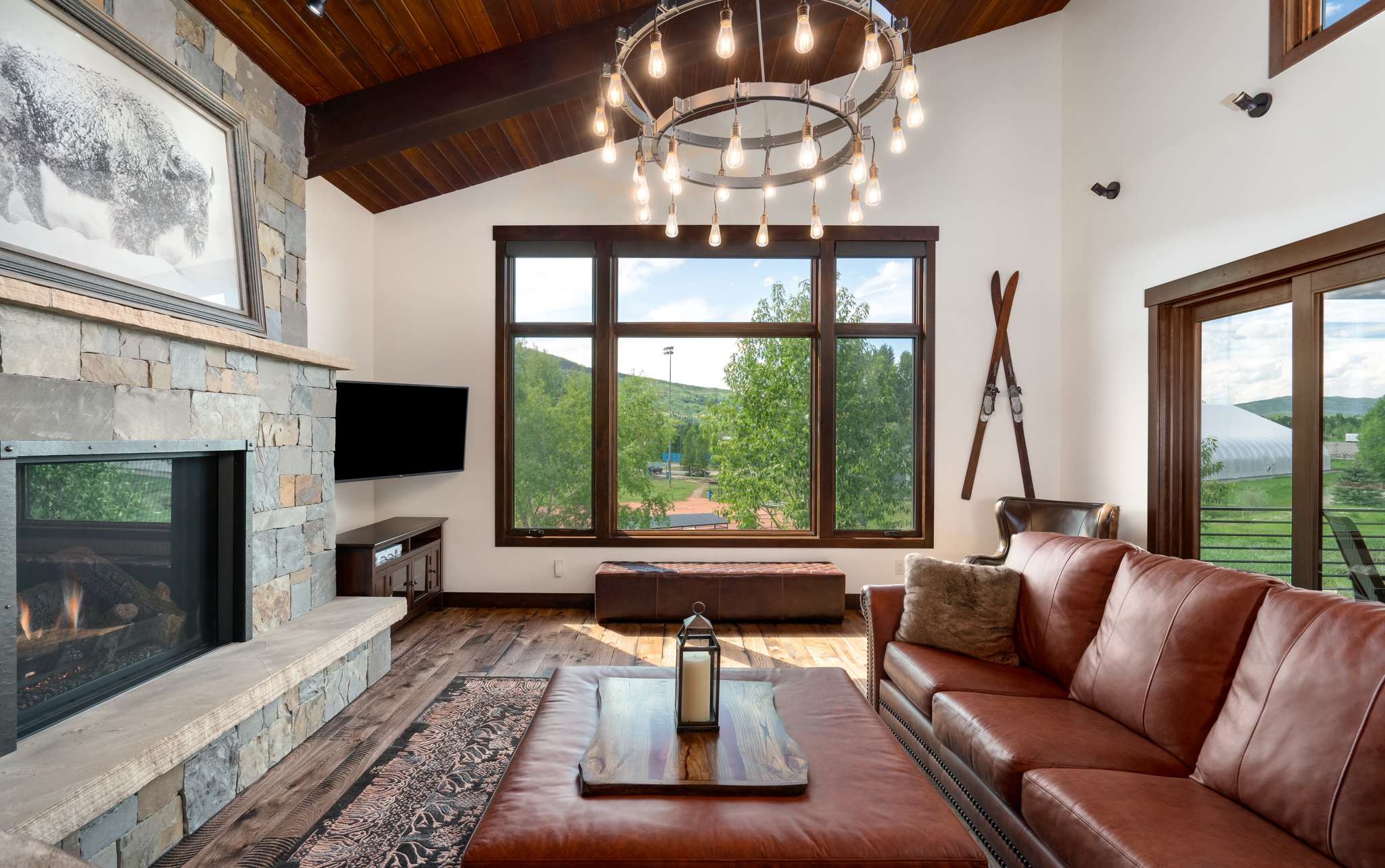 5 of 42. Spacious "Great Room" with mountain views, a stone fireplace, and modern fixtures, perfect for gatherings. The open floor plan connects the great room to the kitchen and dining areas. Sliding glass doors open to a back deck featuring Emerald Mountain views.