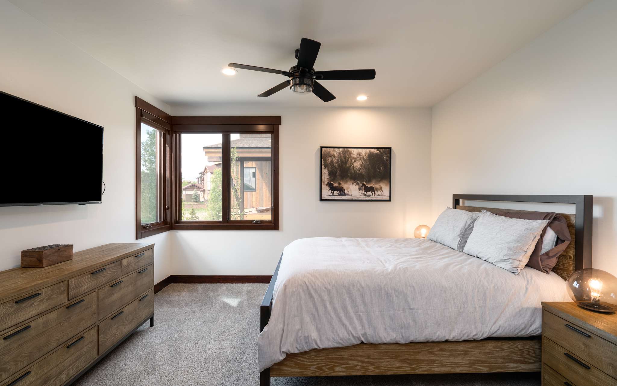 19 of 42. Modern bedroom with ample natural light, featuring a cozy bed, sleek furniture, and scenic window views.