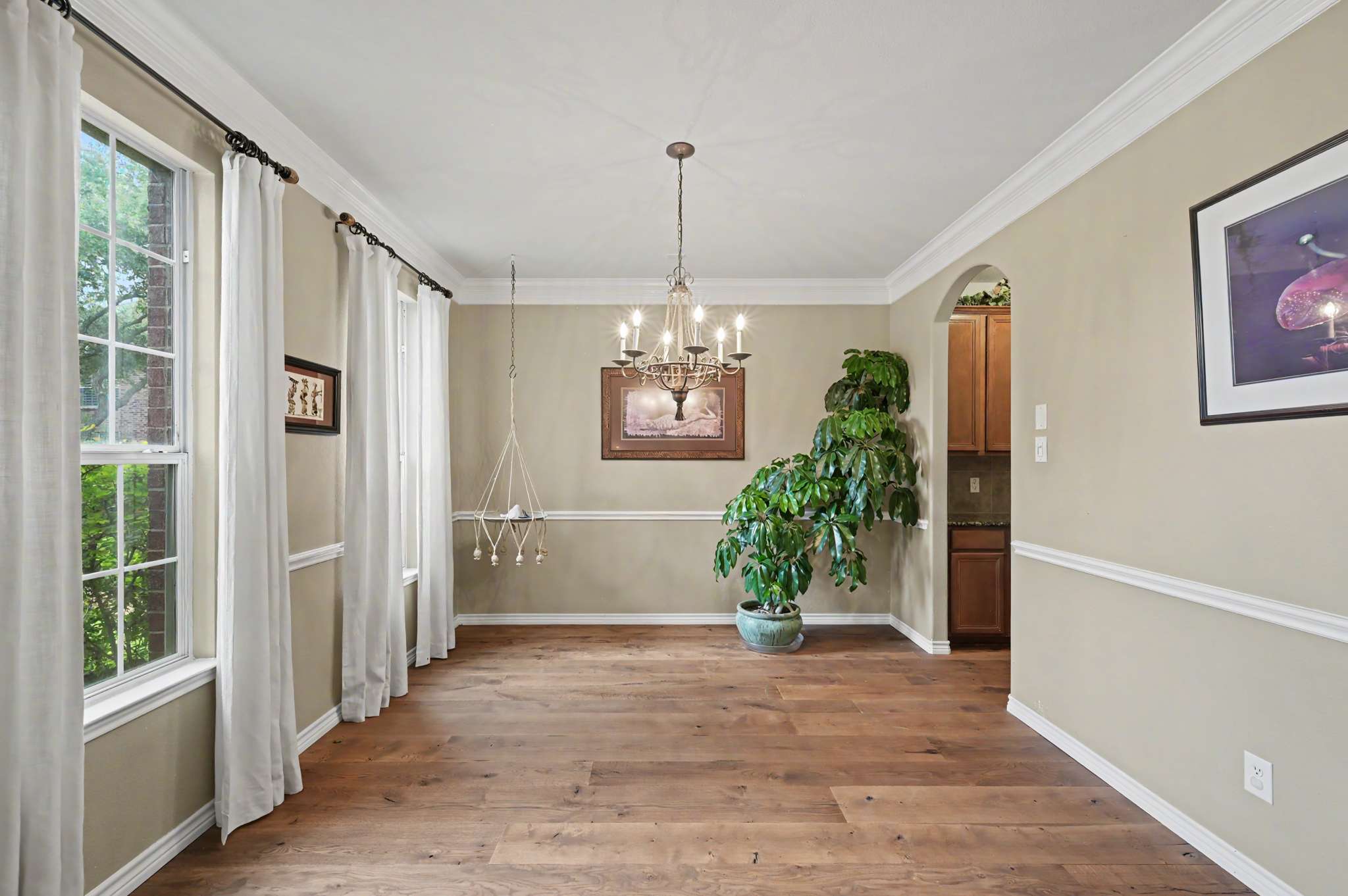 23 of 71. Spacious dining area with ample natural light, featuring a chandelier and lush greenery for a vibrant atmosphere.