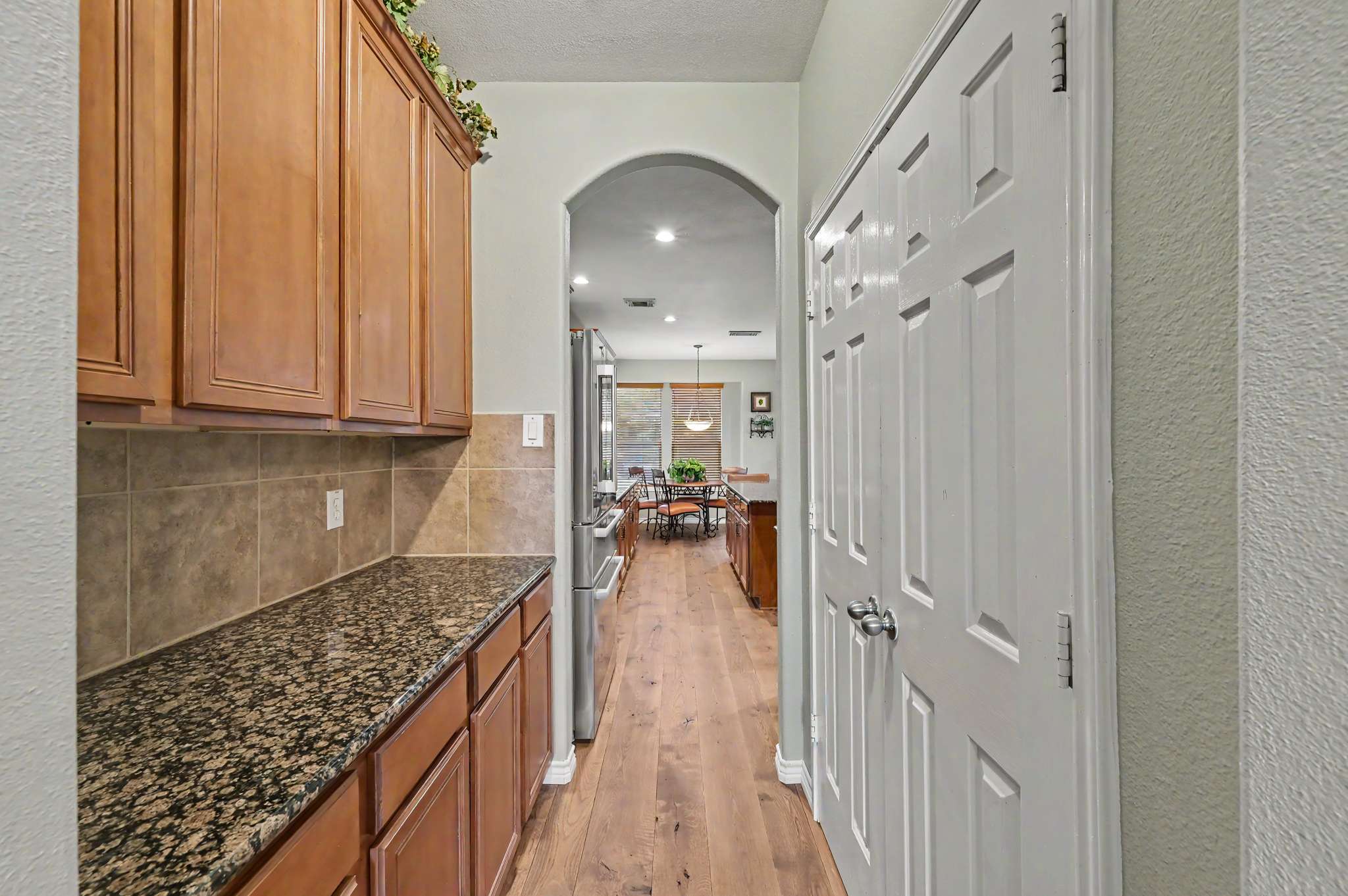 25 of 71. Modern kitchen with rich wood cabinetry, leading into a spacious living area filled with natural light.