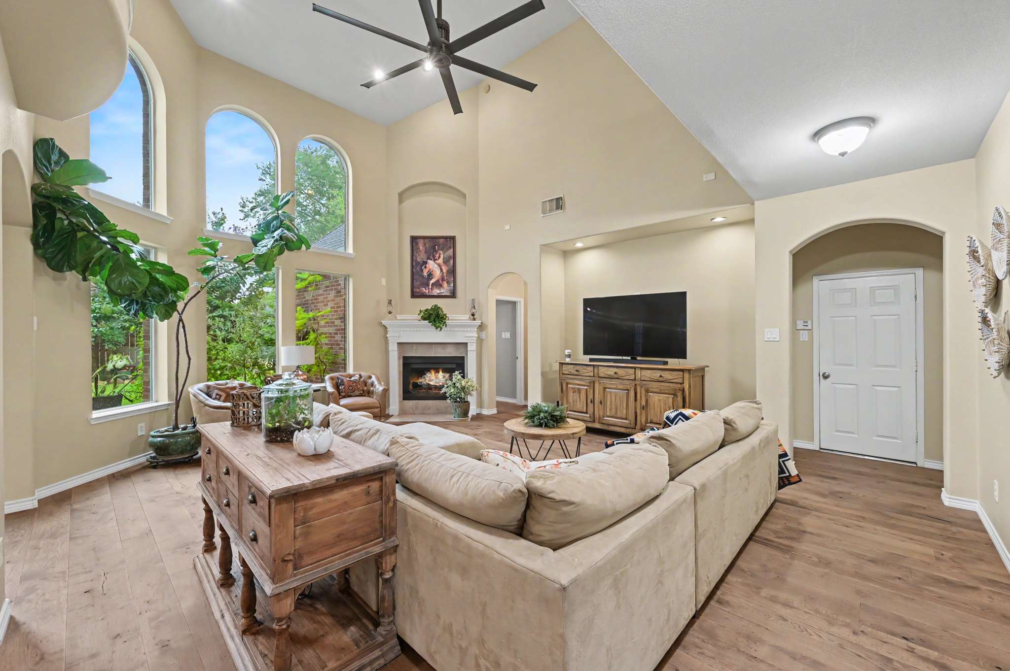26 of 71. Bright and inviting living room with high ceilings, fireplace, and large windows showcasing beautiful outdoor views.