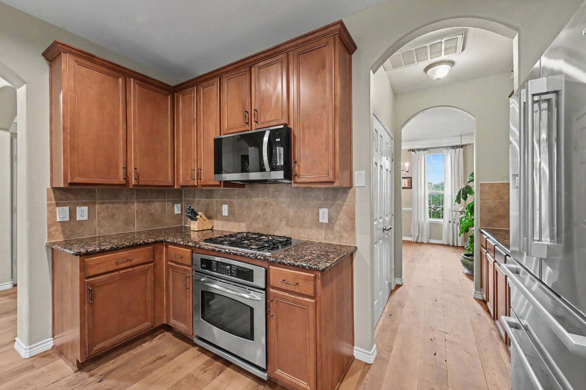 33 of 71. Contemporary kitchen featuring wood cabinets, granite countertops, stainless steel appliances, and an inviting open layout.