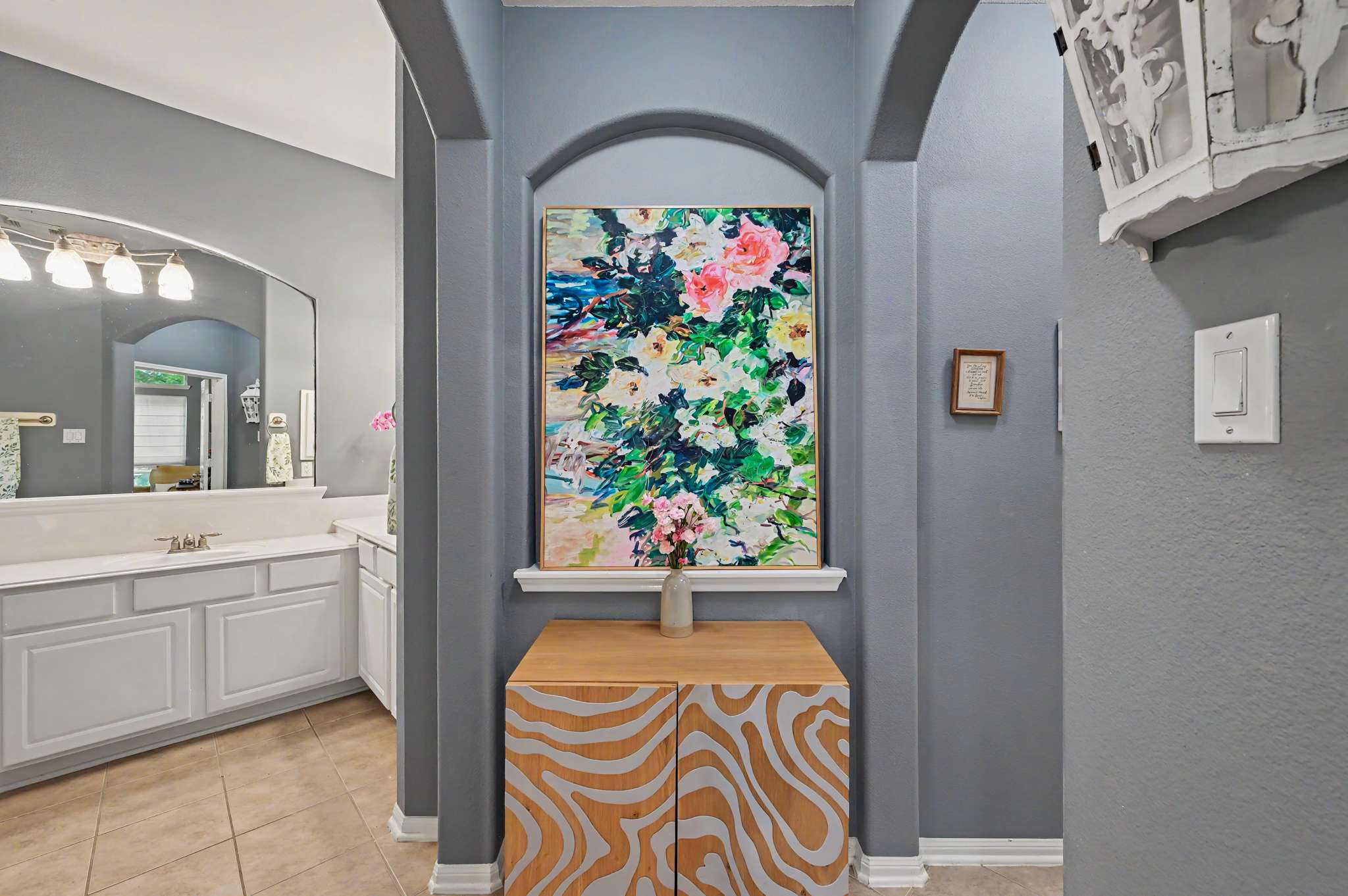 37 of 71. Bright entryway featuring a colorful artwork and an eye-catching patterned console table, leading to a spacious bathroom.