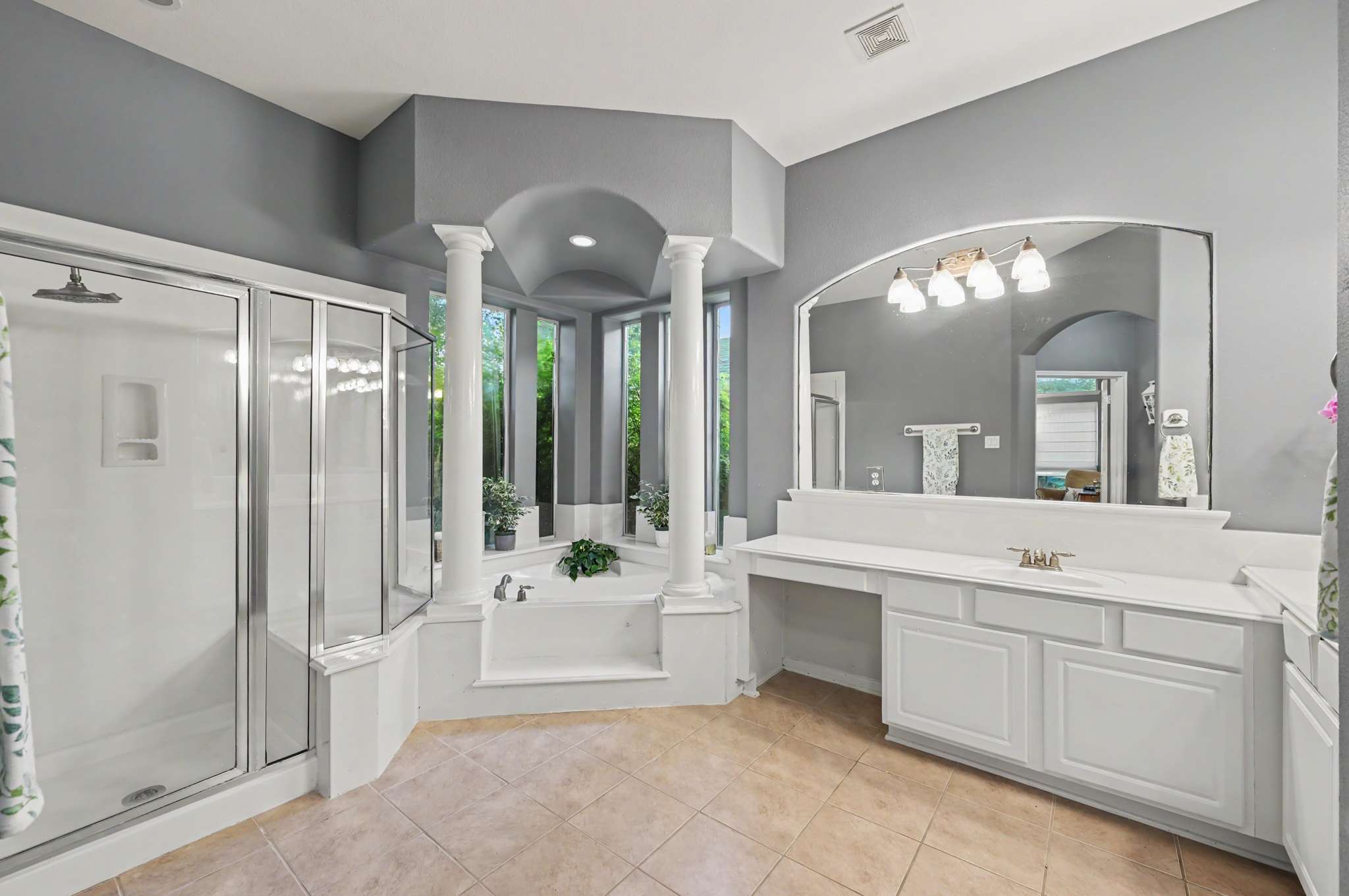8 of 71. Spacious bathroom featuring a large soaking tub, dual vanities, and natural light from expansive windows.