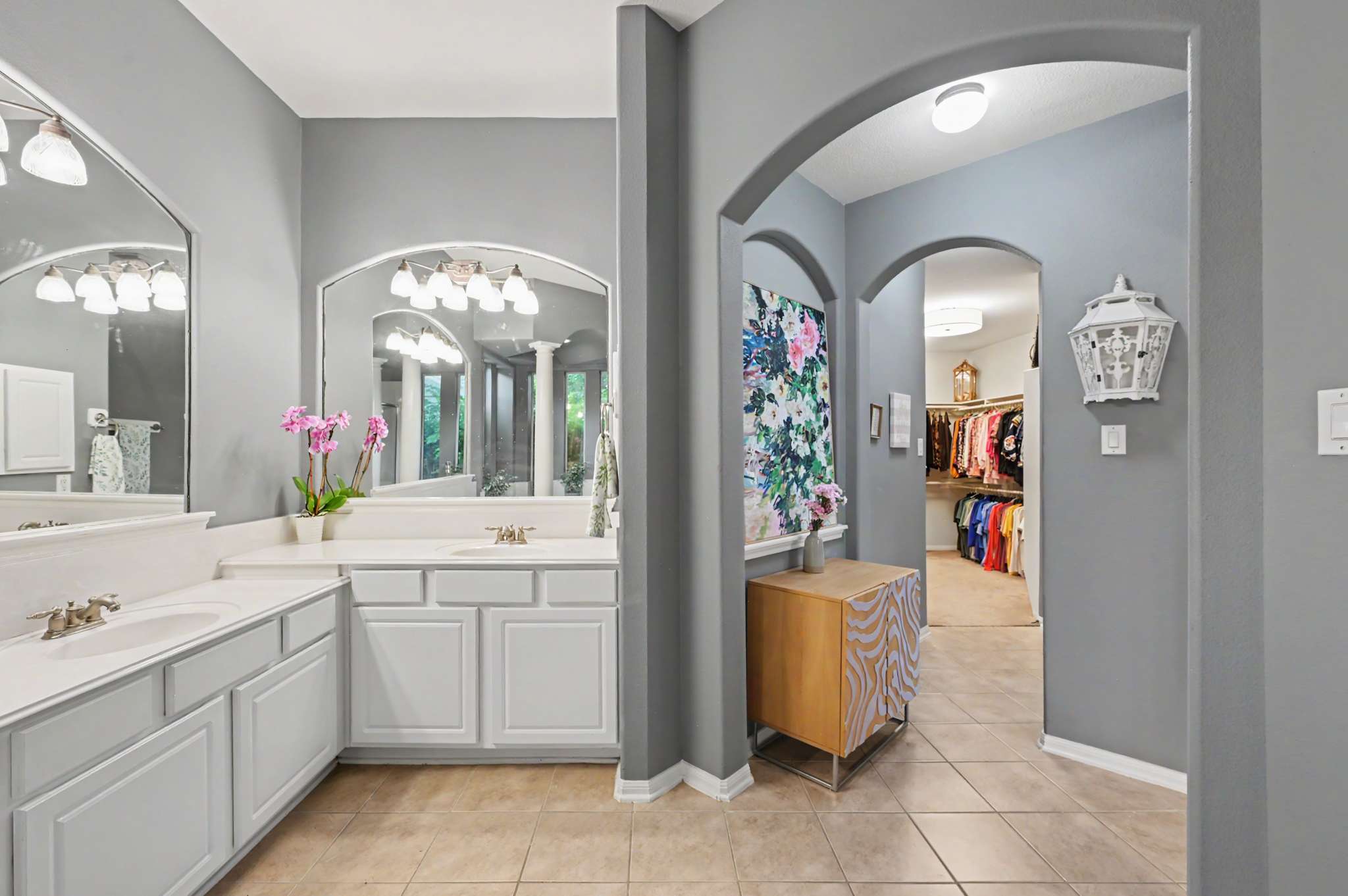 38 of 71. Spacious bathroom with double sinks, modern lighting, and an inviting pathway to a well-organized closet.