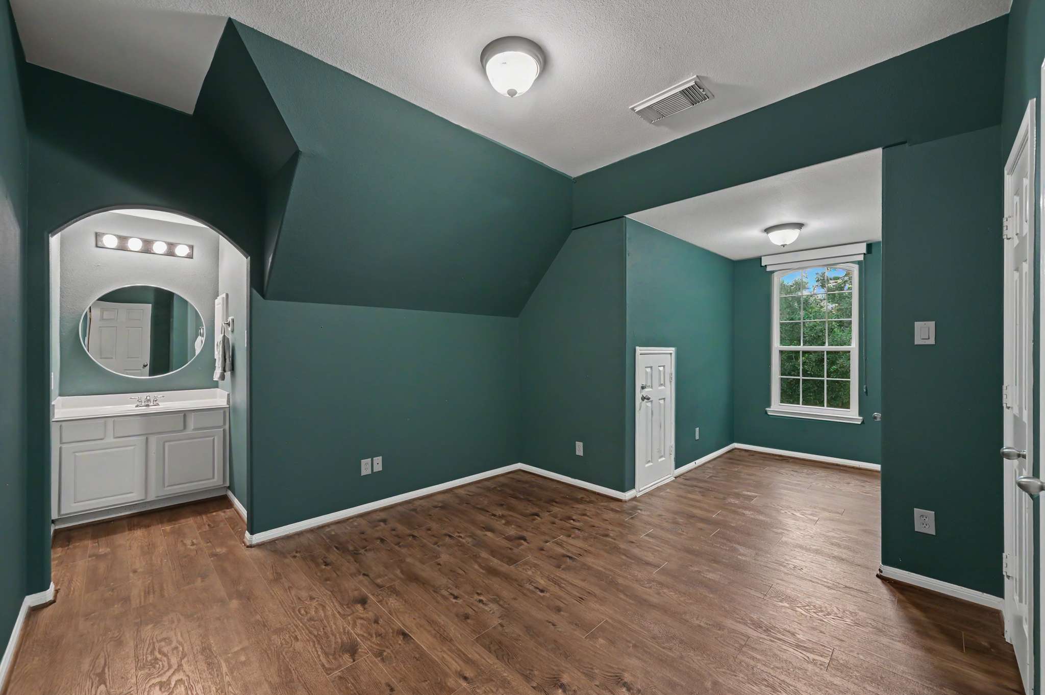47 of 71. Bright, spacious room featuring unique architecture, hardwood floors, and an adjoining bathroom setup for convenience.