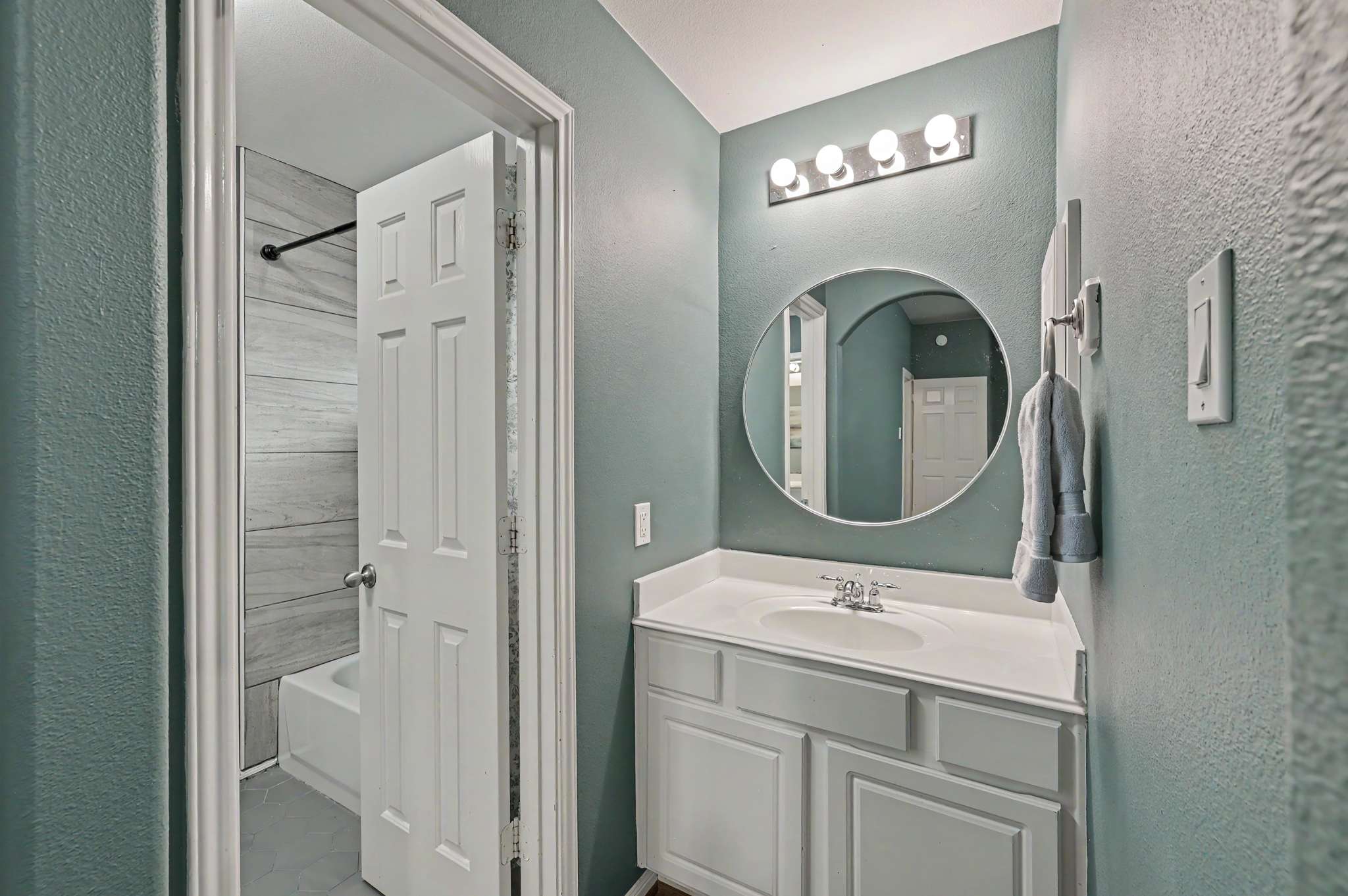 50 of 71. Modern bathroom featuring a spacious vanity, circular mirror, and calming blue walls for a refreshing ambiance.