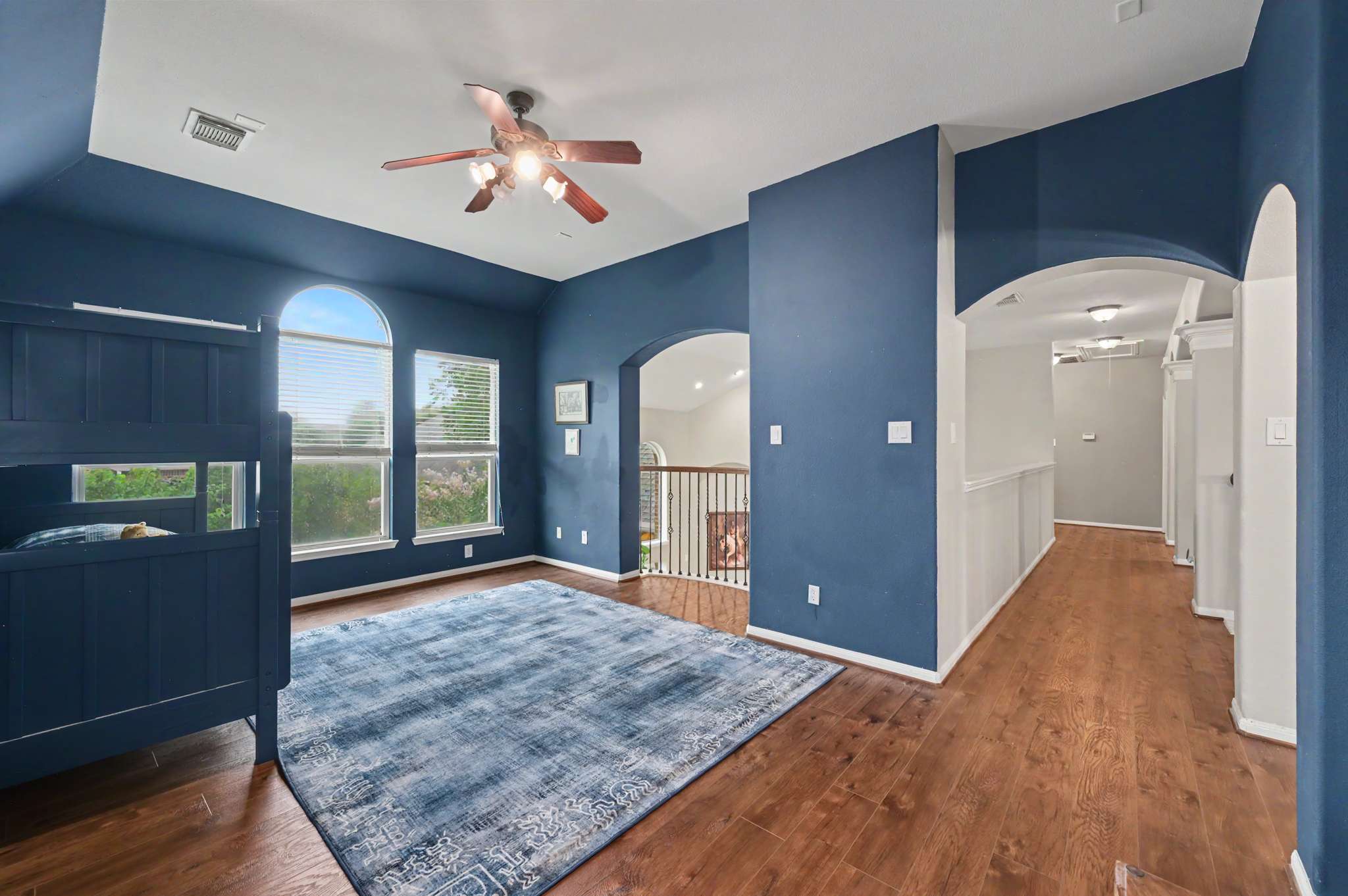 53 of 71. Spacious room featuring bold blue walls, ample natural light, and unique architectural details, perfect for versatile use.
