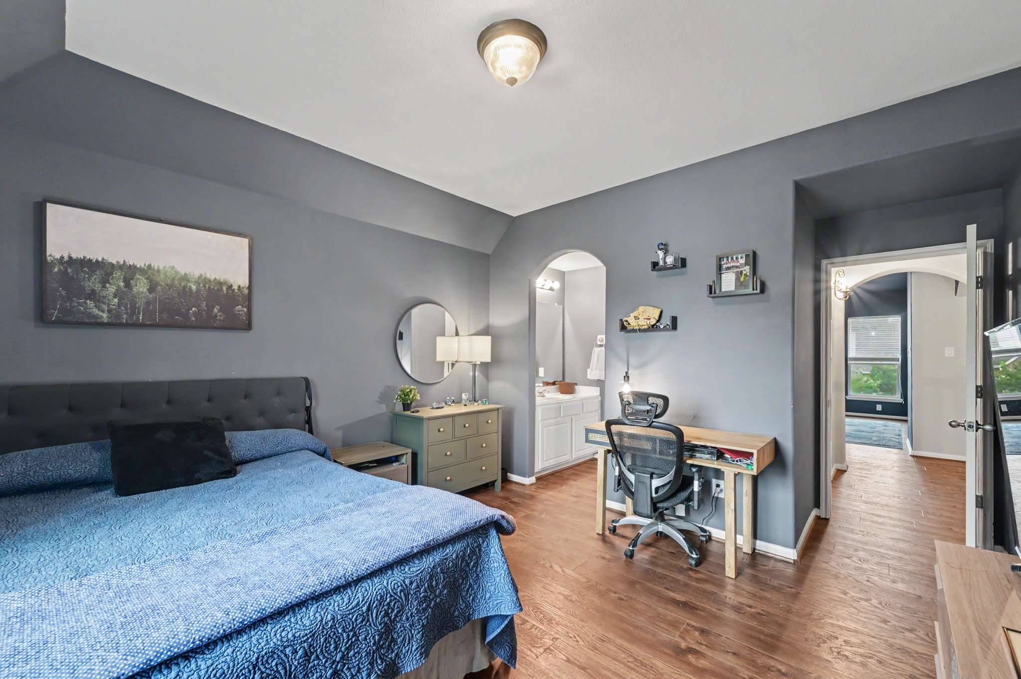 57 of 71. Bright and spacious bedroom featuring modern decor, dedicated workspace, and direct access to a stylish bathroom.