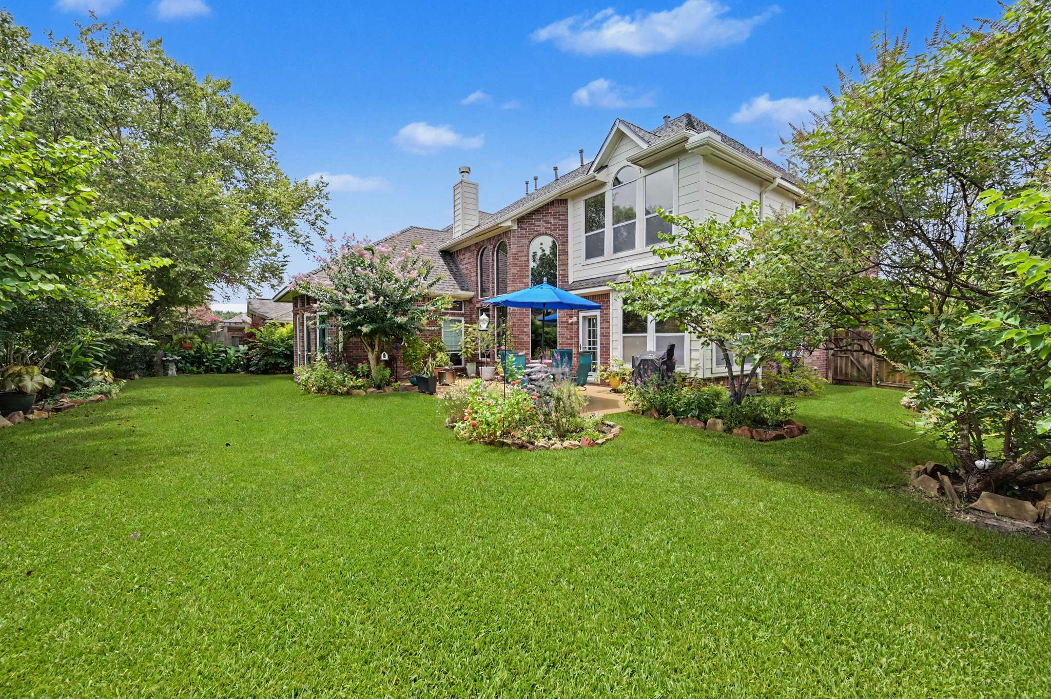 59 of 71. Spacious backyard with lush greenery and inviting patio, perfect for outdoor gatherings and relaxation.