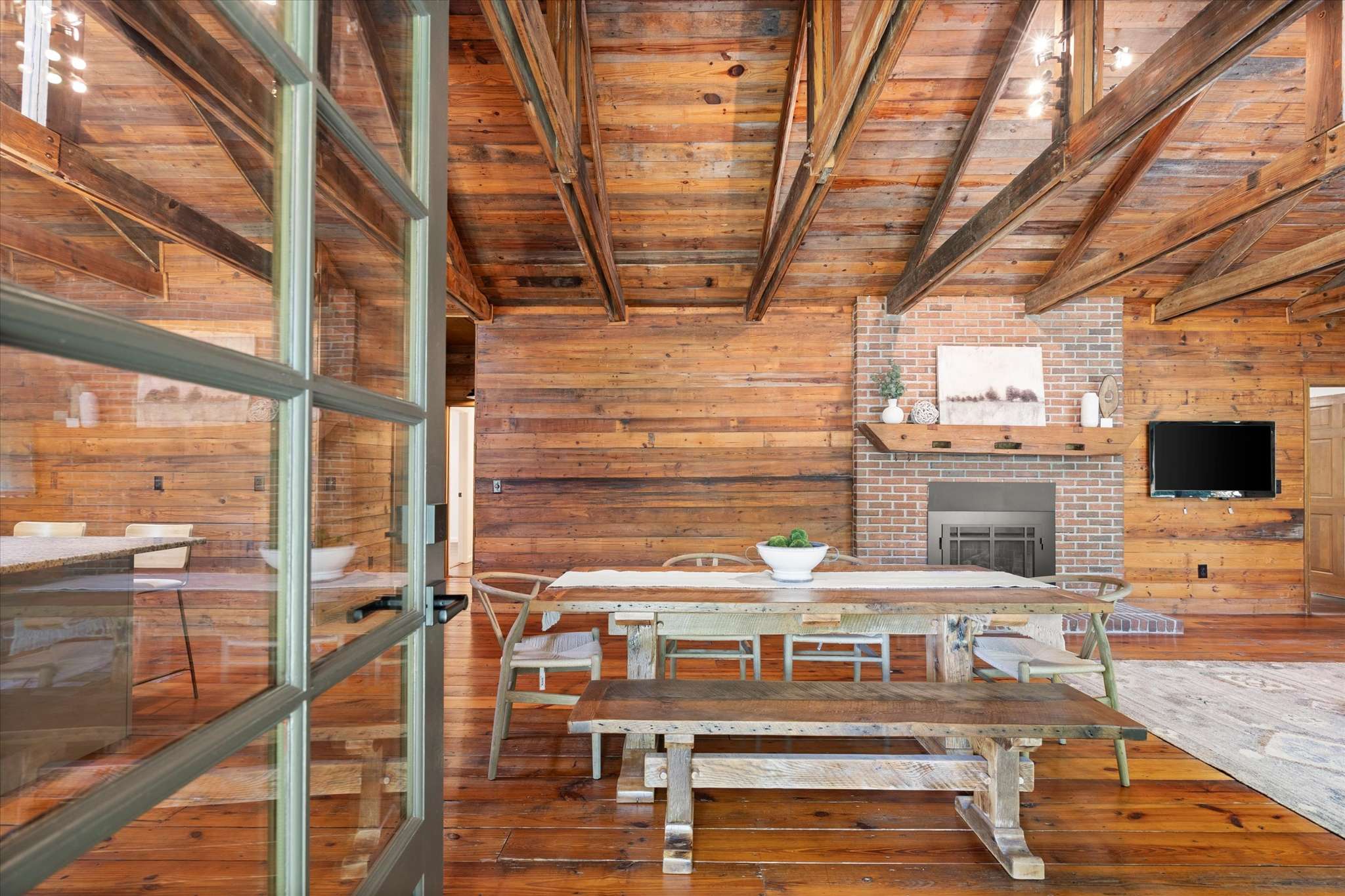 7 of 72. Spacious open-concept living area features rustic wood beams, inviting dining space, and a cozy fireplace.