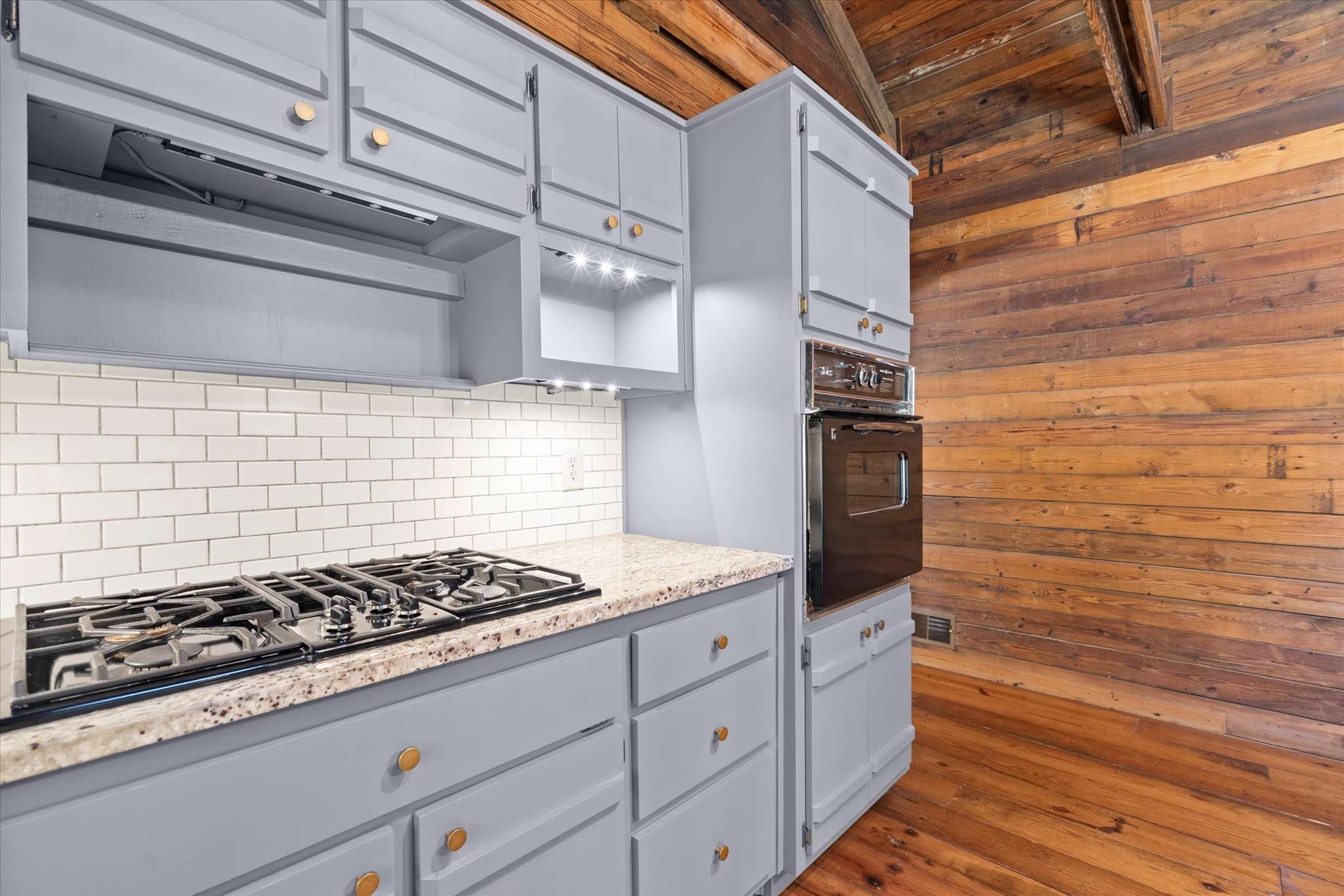 28 of 72. This modern kitchen features sleek cabinetry, a gas range, and rustic wood accents for a unique touch.