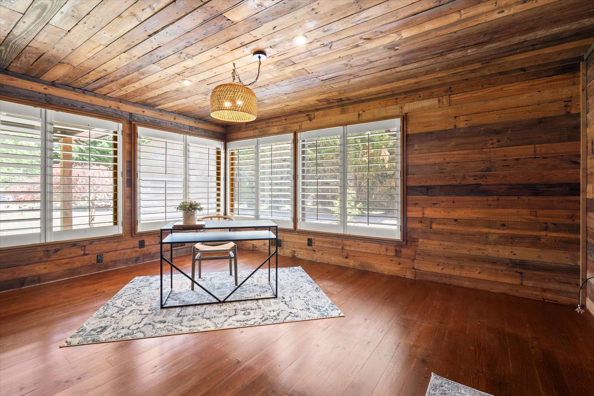 30 of 72. Bright workspace featuring wood-paneled walls, ample natural light, and cozy views from large windows.