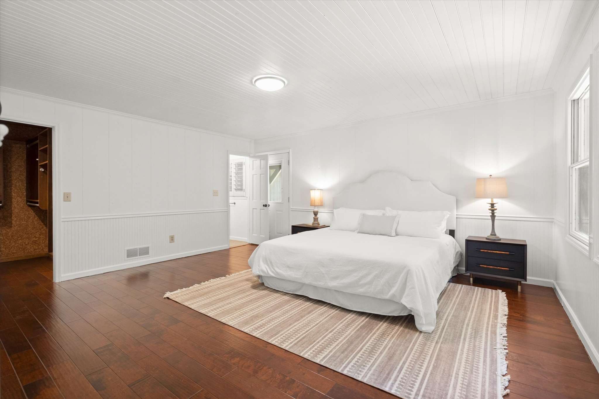5 of 72. Spacious bedroom featuring hardwood floors, ample natural light, and convenient access to an adjacent bathroom.