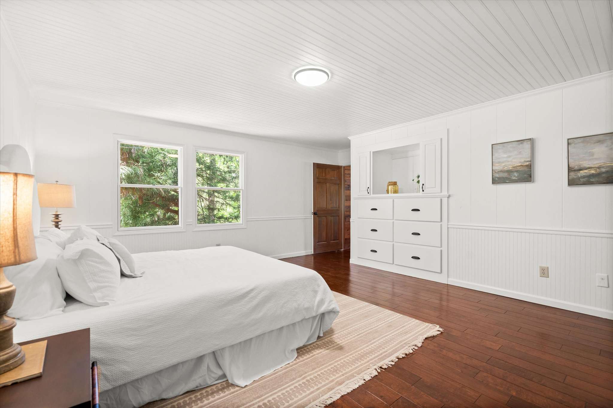 34 of 72. Bright and spacious bedroom featuring large windows, hardwood floors, and ample storage for comfort and convenience.