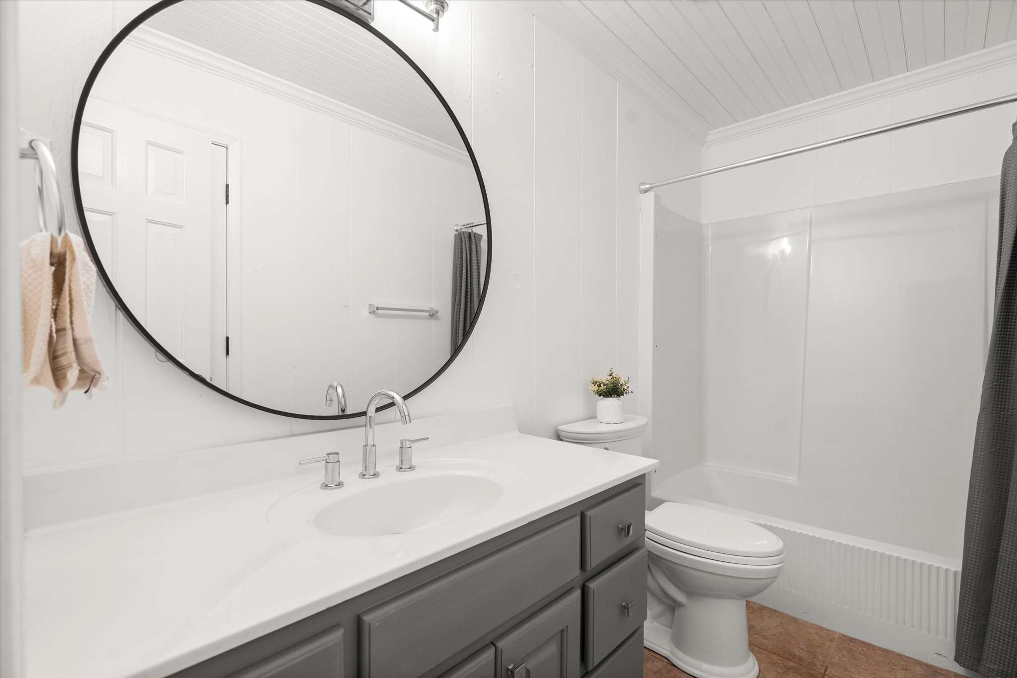 38 of 72. Bright and modern bathroom featuring a circular mirror, spacious vanity, and a sleek walk-in shower.