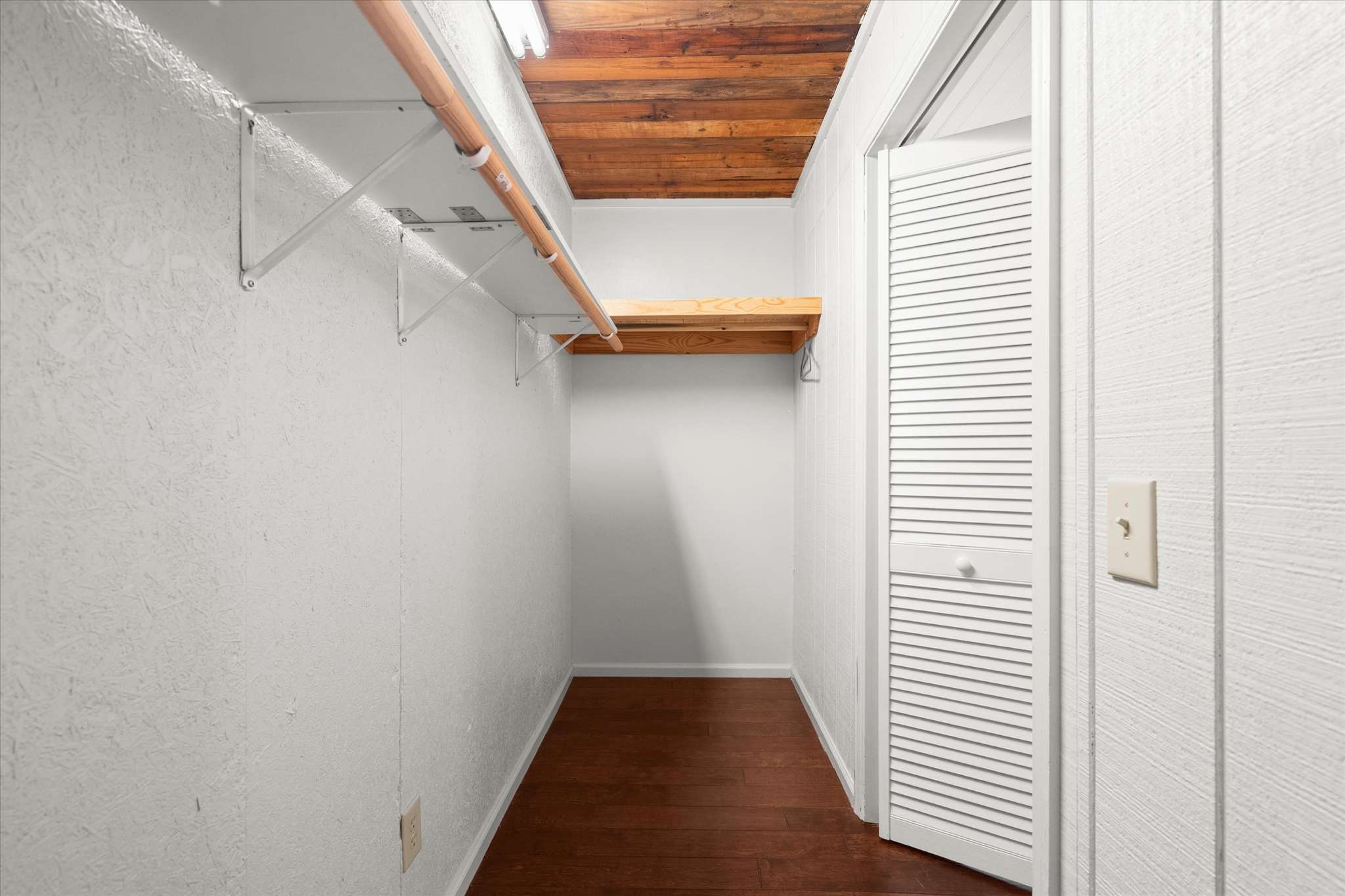 41 of 72. Spacious walk-in closet featuring ample storage and wooden accents, perfect for organizing your wardrobe.
