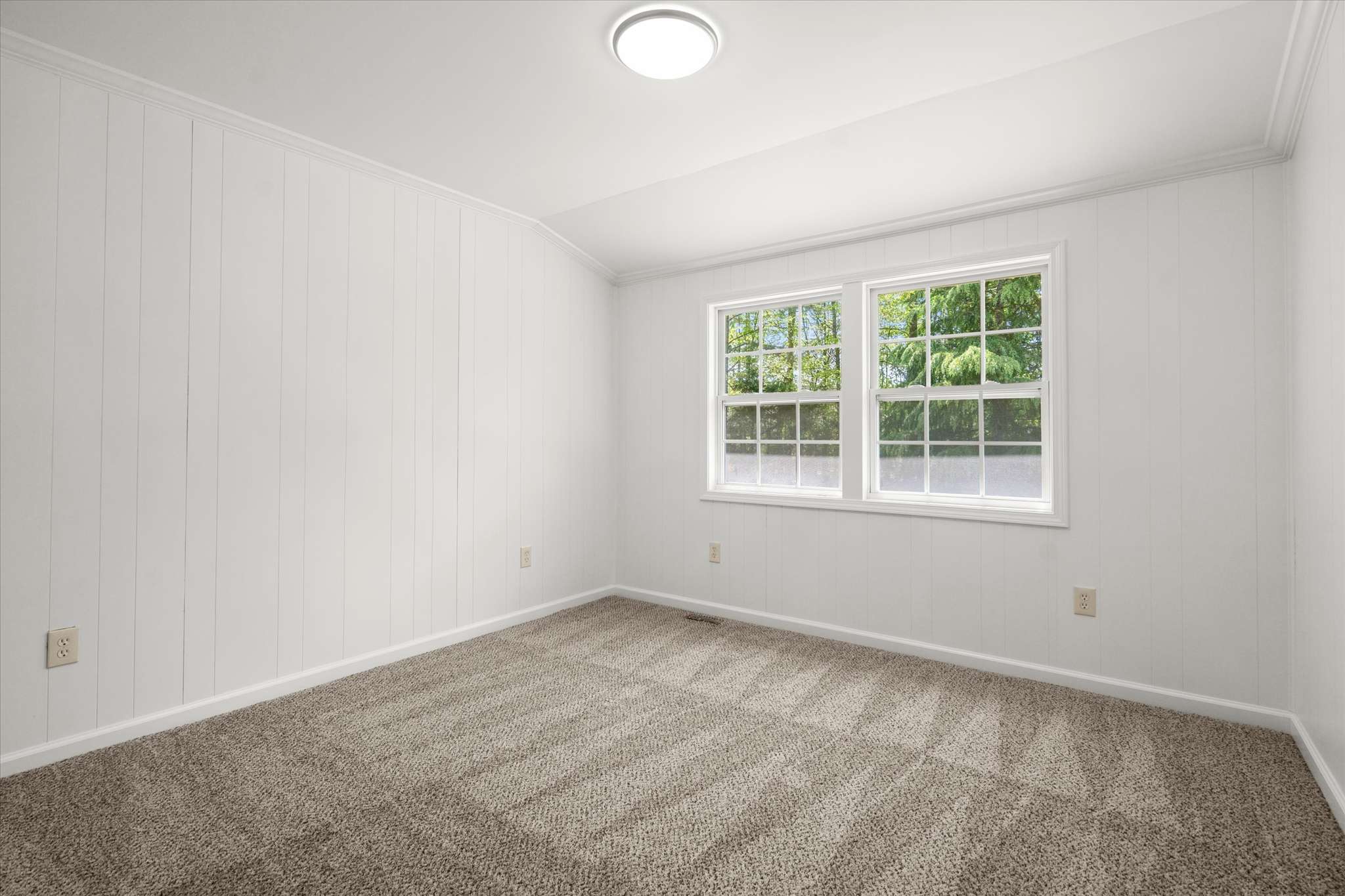 42 of 72. Bright, spacious room with freshly painted walls and natural light streaming in from dual windows.