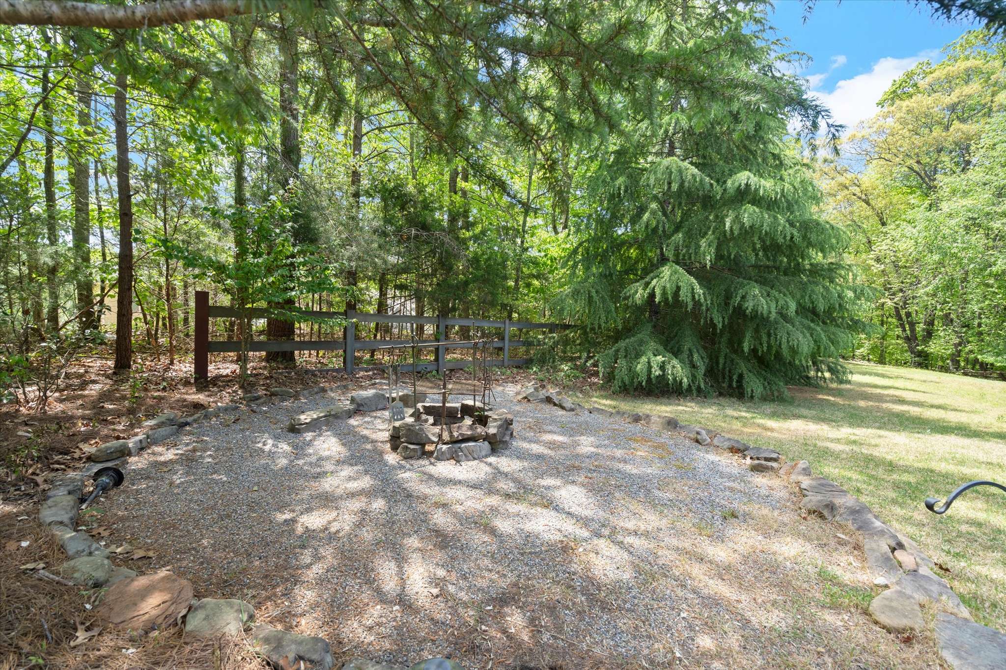 50 of 72. Discover a private outdoor space featuring a stone fire pit surrounded by lush greenery and tall trees.