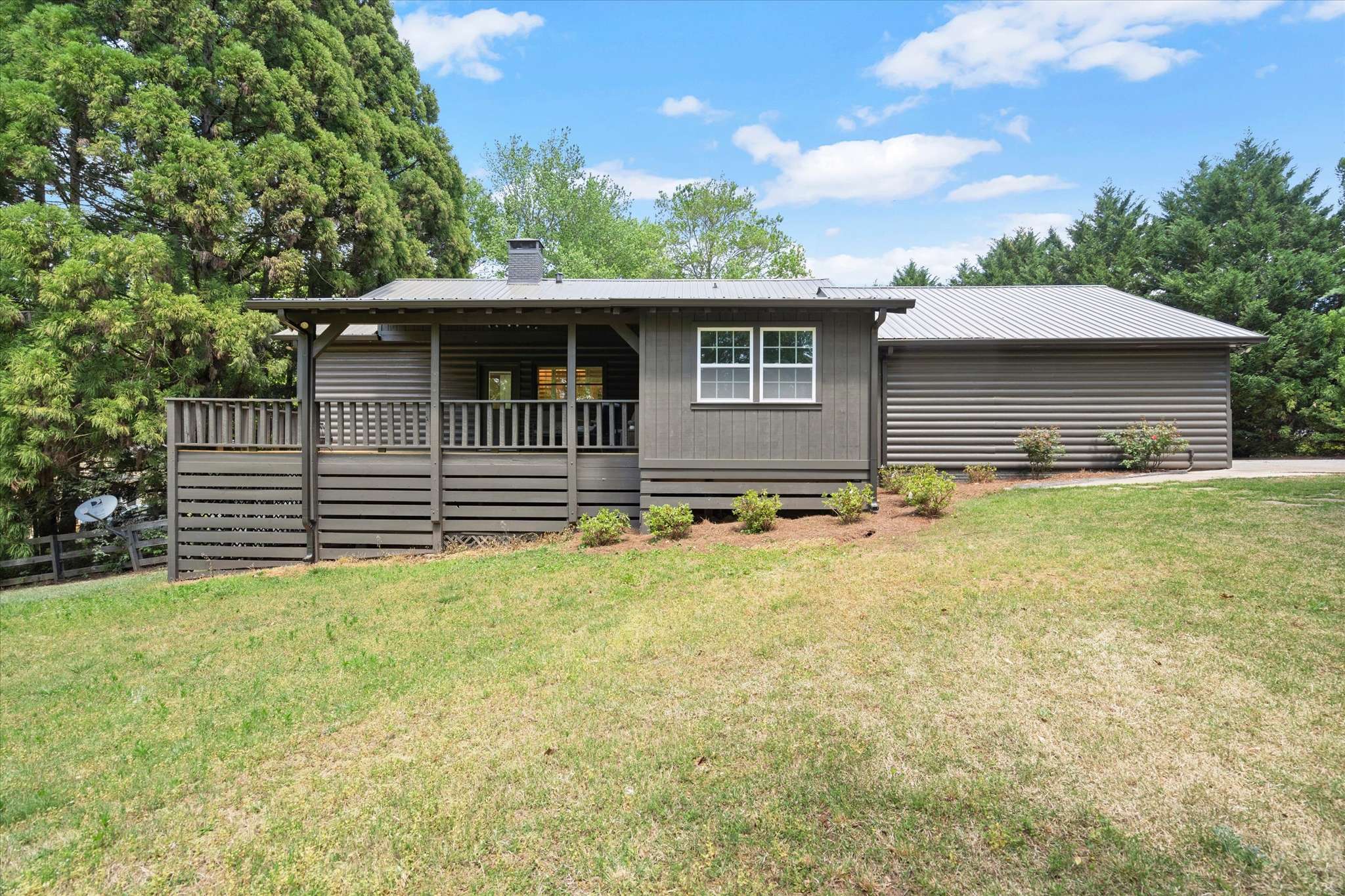 52 of 72. Welcoming home surrounded by lush greenery, featuring a spacious deck and inviting exterior design.