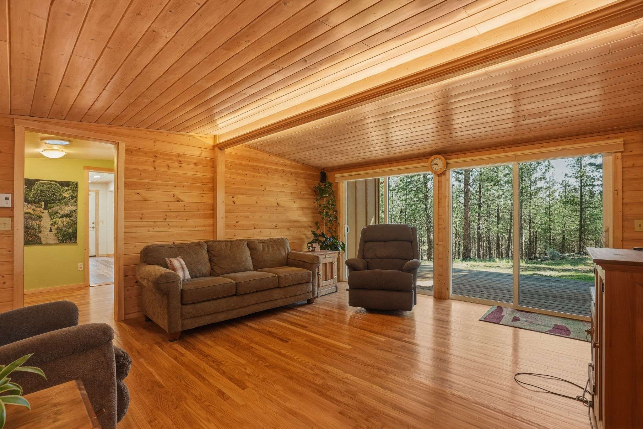 8 of 61. Cozy, wood-paneled living space with two sliders offering abundant natural light and scenic forest views.