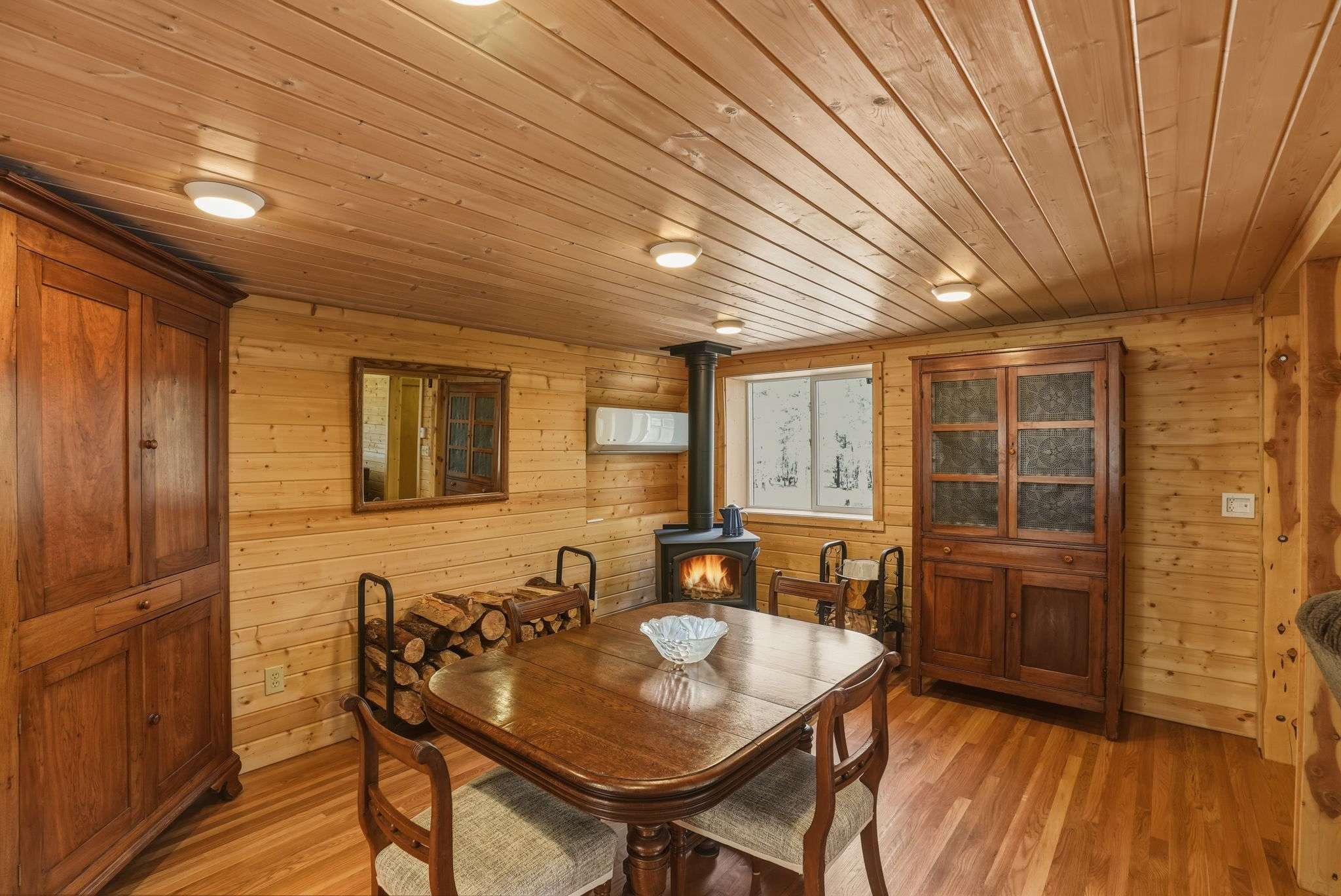 15 of 61. Cozy wooden interior featuring a dining area, and a wood stove for an inviting atmosphere.