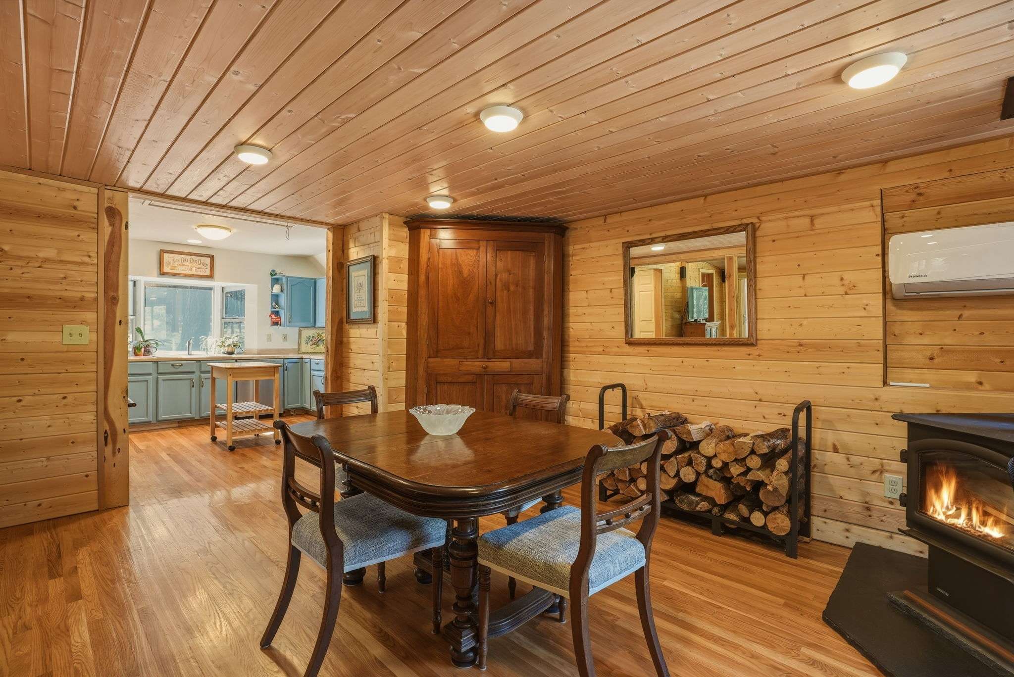 17 of 61. Cozy dining area with warm wood accents, featuring a wood stove and seamless flow to the kitchen.