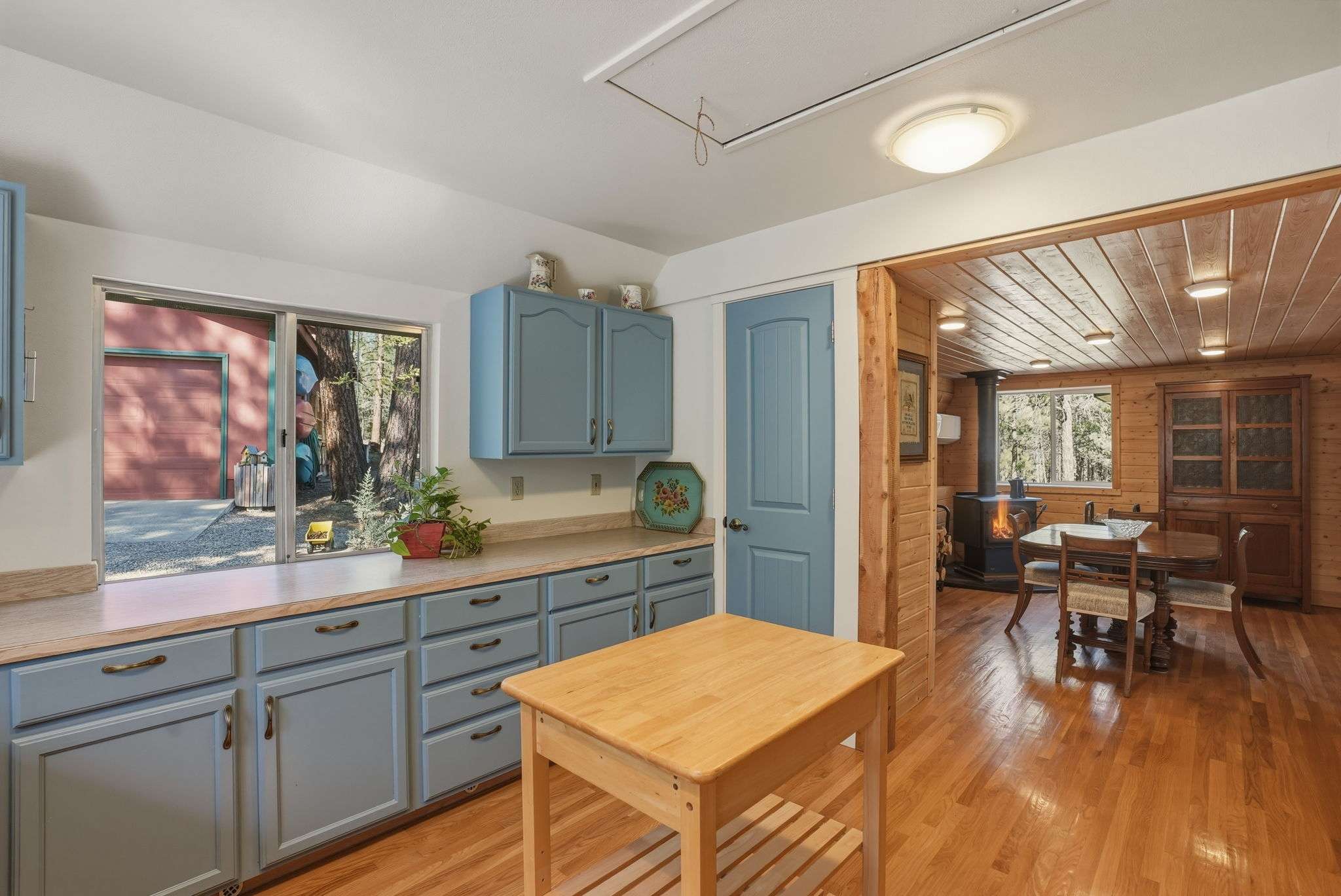 18 of 61. Bright kitchen featuring blue cabinetry, natural wood elements, and inviting views of the outdoor surroundings.