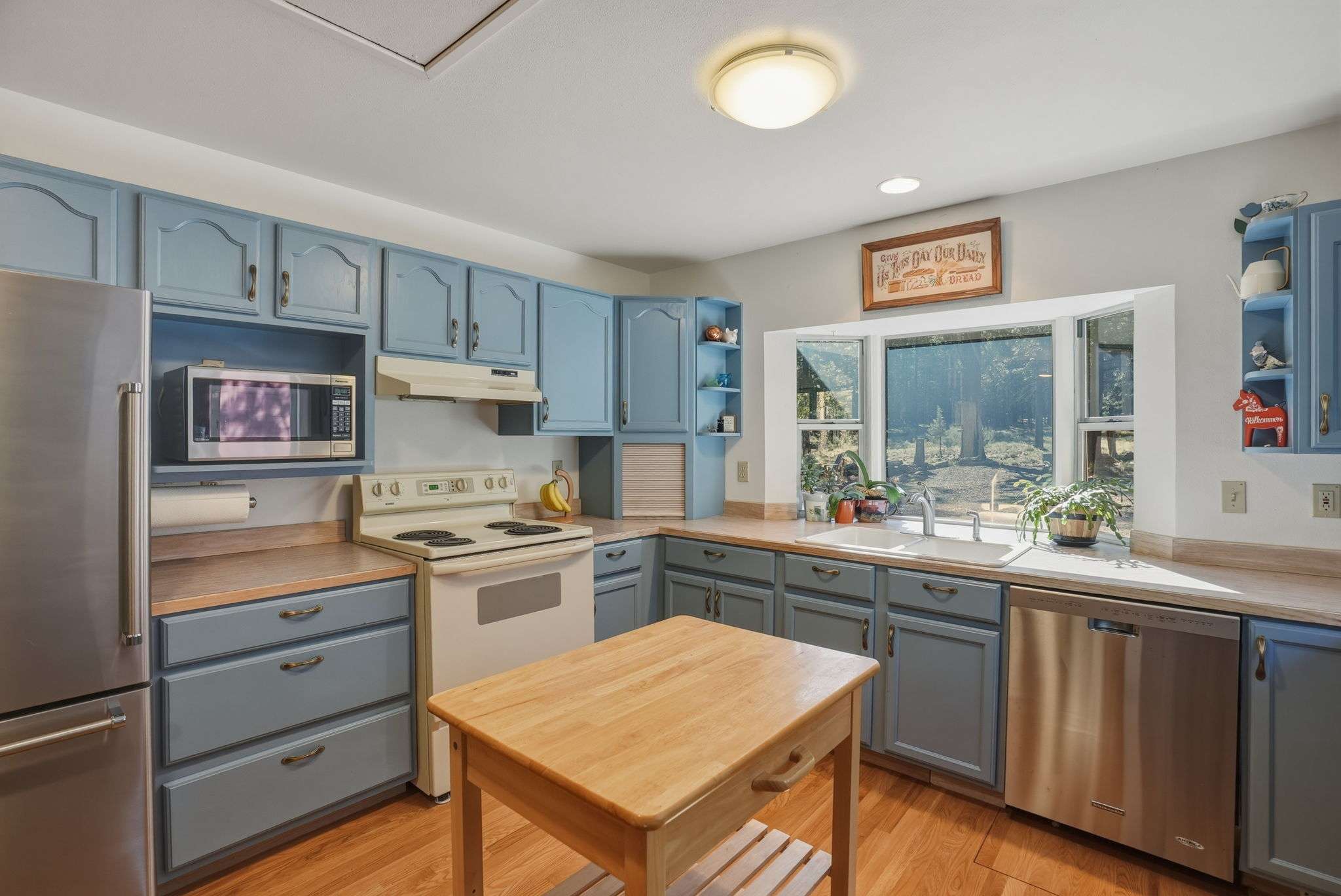 21 of 61. Bright kitchen featuring blue cabinetry, modern appliances, and abundant natural light for a welcoming cooking space.