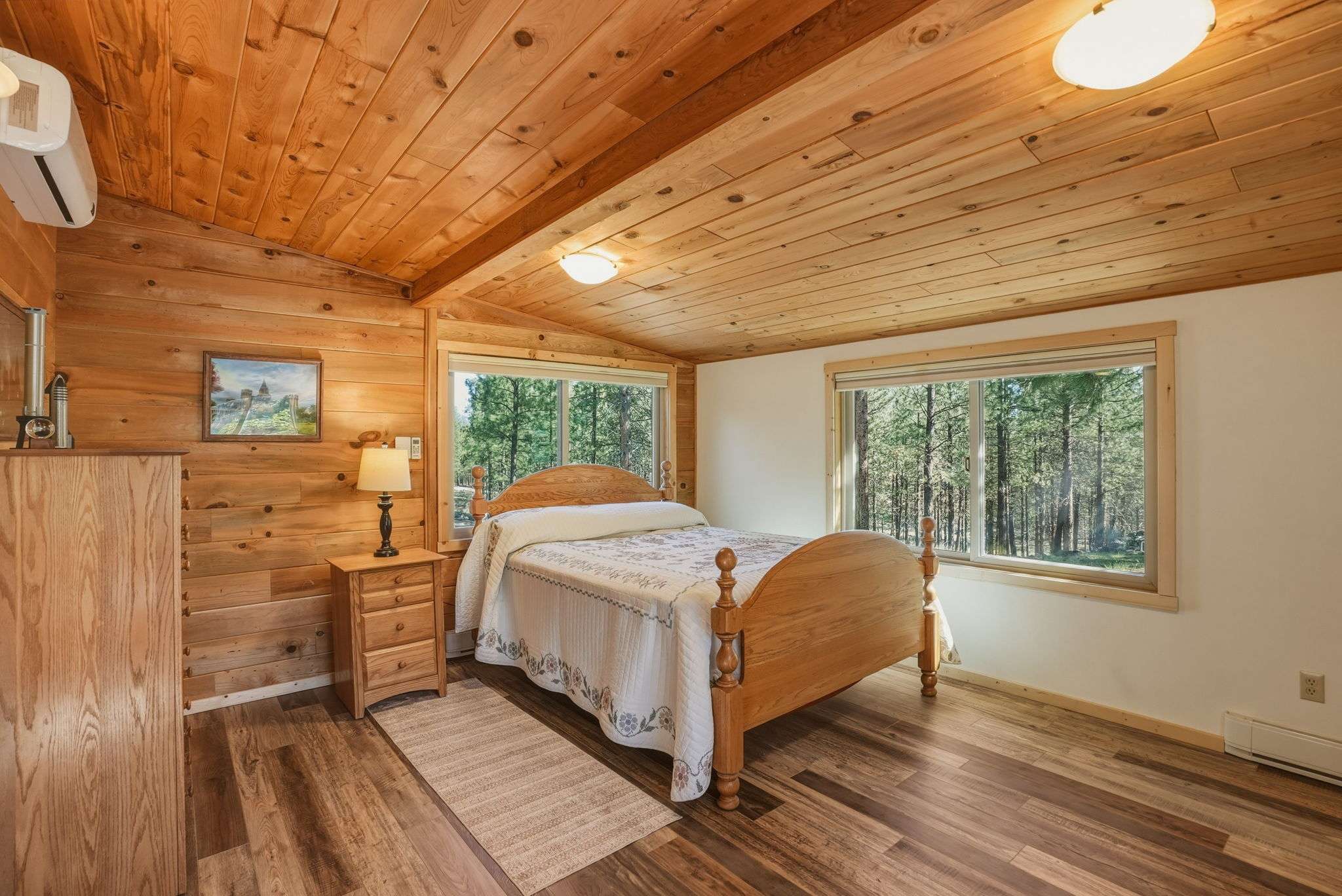 26 of 61. Cozy bedroom with wood paneling, large windows showcasing natural light, and a framed view of Black Butte and Mt. Jefferson.