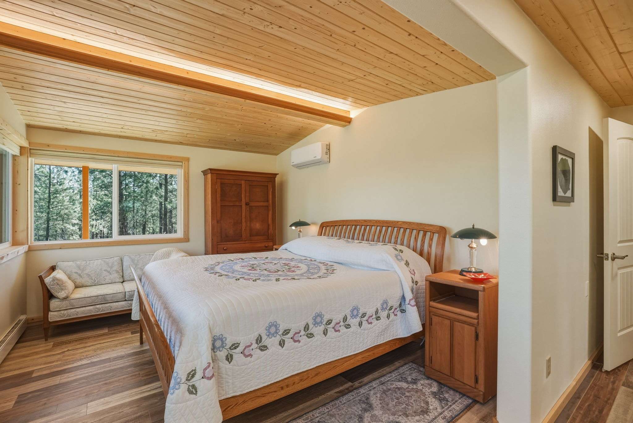 31 of 61. Bright and airy bedroom featuring large windows, natural wood accents, and cozy seating for relaxation.