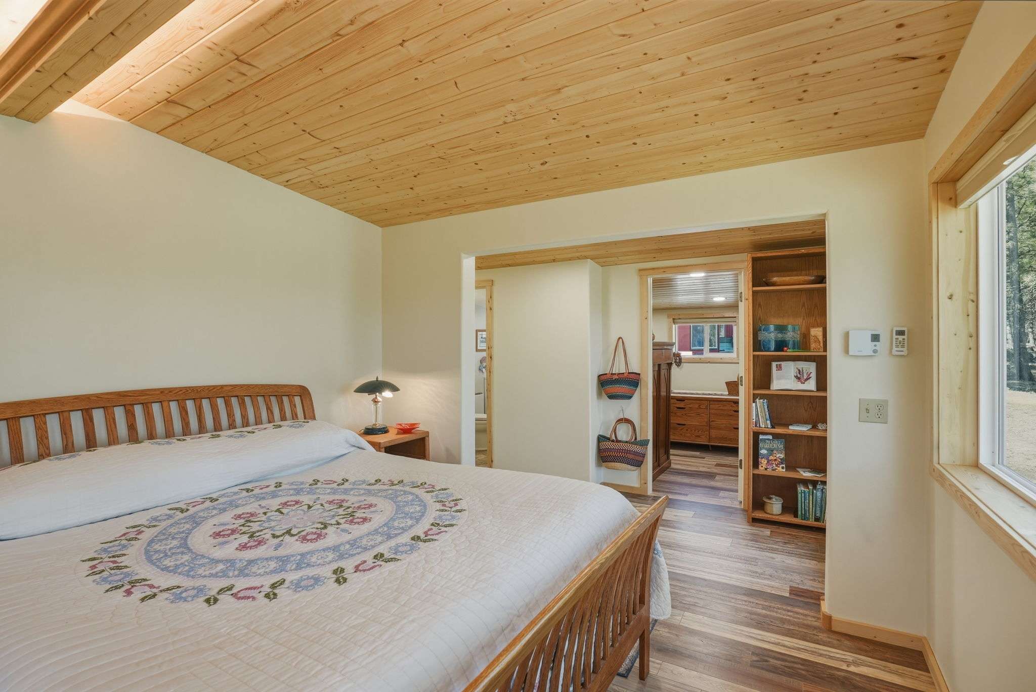 35 of 61. Bright and inviting bedroom featuring wood accents, abundant natural light, and convenient access to adjoining spaces.