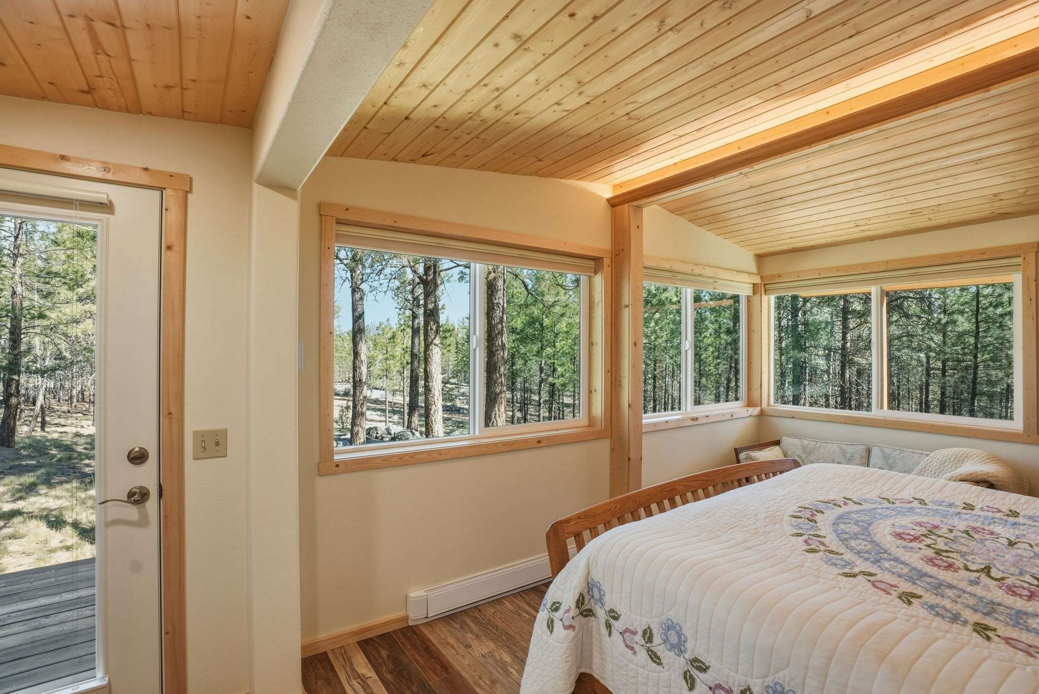 30 of 61. Bright and airy bedroom featuring expansive windows that invite natural light and views of surrounding nature.