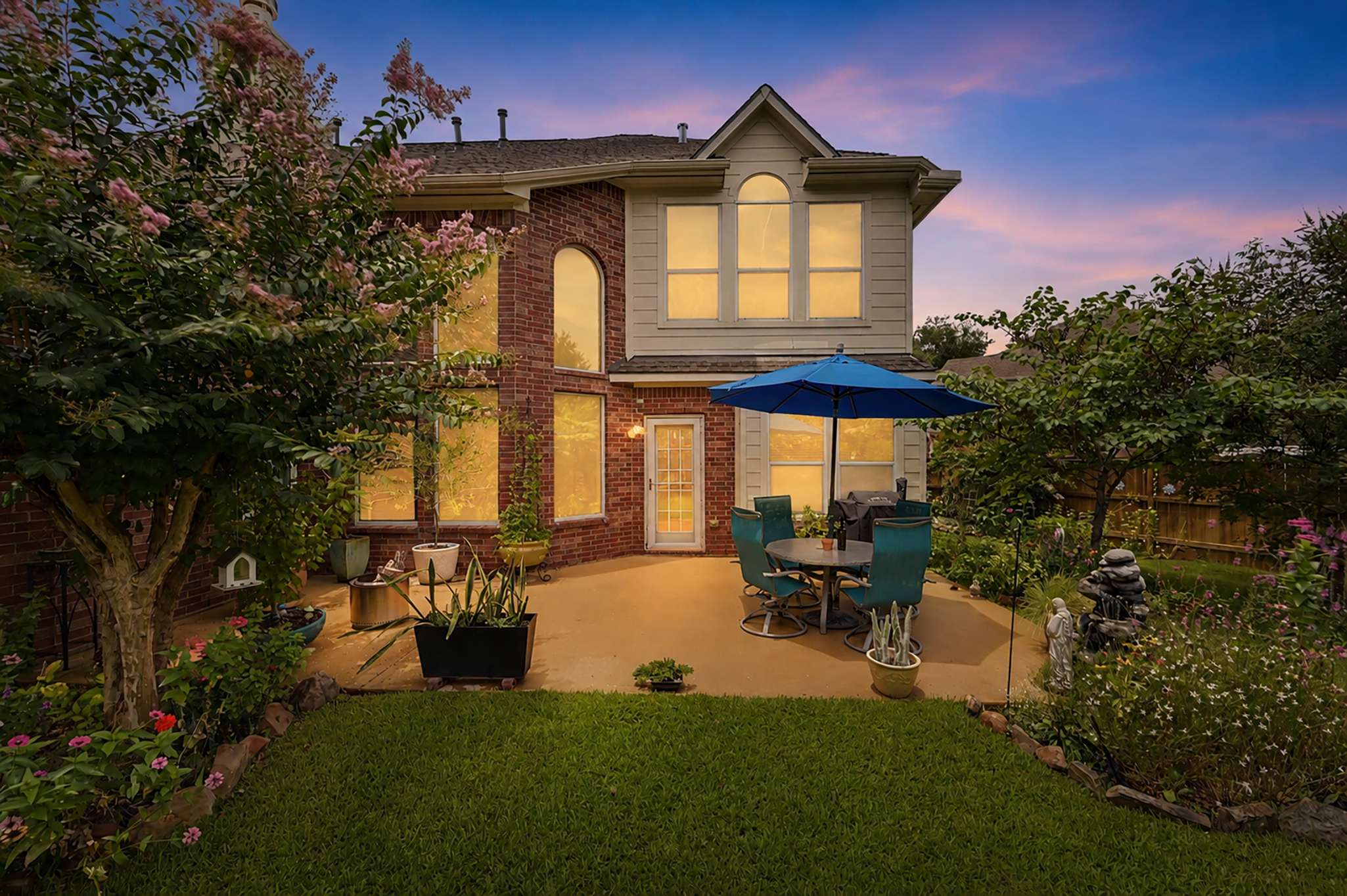13 of 71. Enjoy outdoor living in this inviting backyard, featuring a shaded patio and vibrant garden elements.