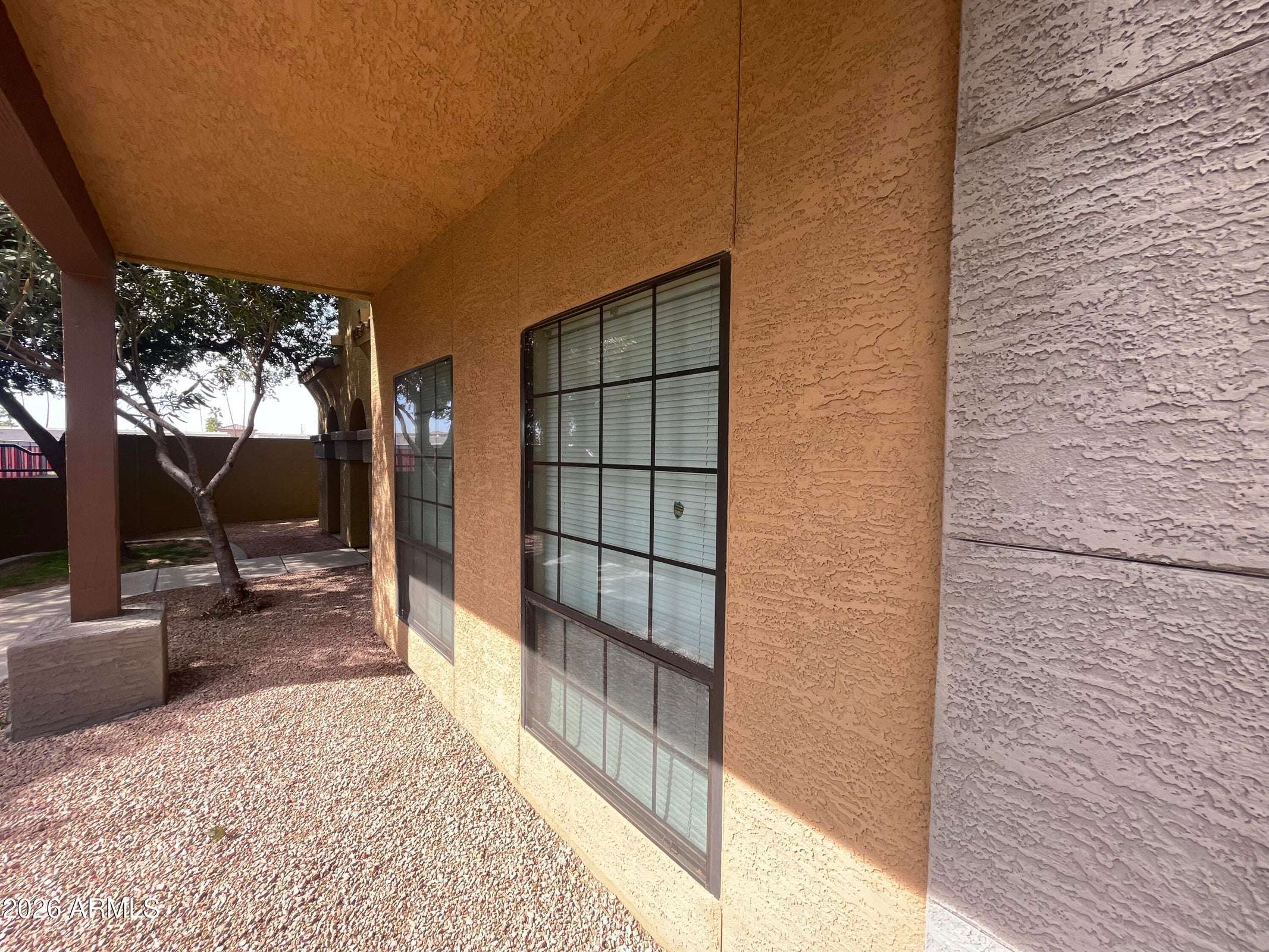 6 of 26. The covered front patio provides a relaxing outdoor sitting area surrounded by mature landscaping and attractive desert scenery within the gated community.