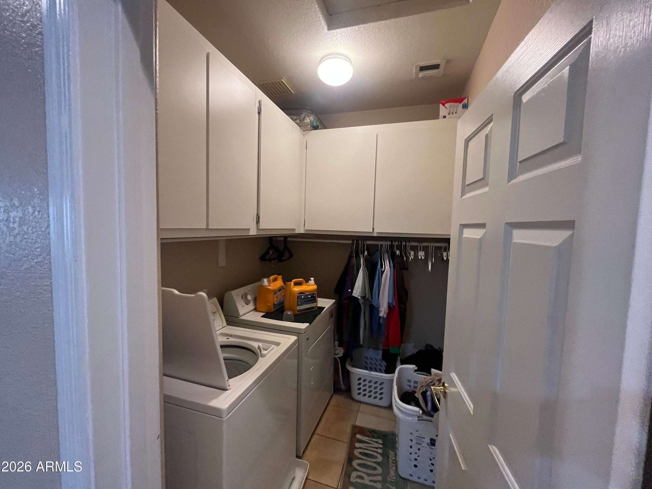 10 of 26. A dedicated interior laundry room offers built-in cabinetry, storage space, and convenient access to keep household chores organized and efficient in this Phoenix home.